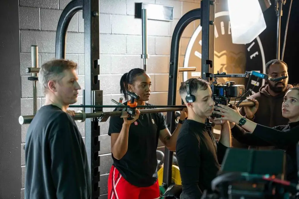 FX Productions Canada A Toronto Video Production crew sets up a camera shot in a gym, with several people adjusting equipment and wearing headsets, surrounded by filming gear. Toronto Video Production Company