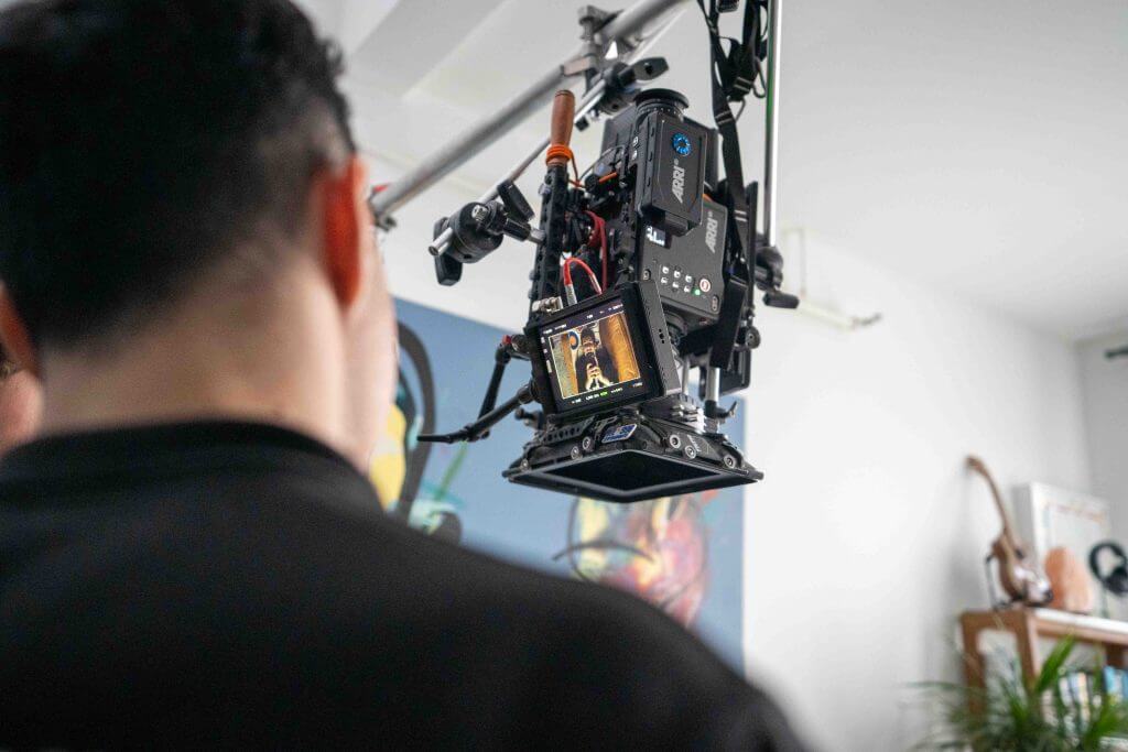 FX Productions Canada A person stands near a professional video camera rig, focused on a screen displaying a scene being filmed indoors by Toronto Video Production experts. Toronto Video Production Company