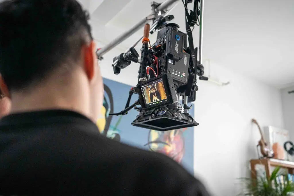 FX Productions Canada A person stands near a professional video camera rig, focused on a screen displaying a scene being filmed indoors by Toronto Video Production experts. Toronto Video Production Company