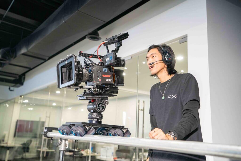 FX Productions Canada A person wearing a headset operates a professional video camera mounted on a tripod in a modern indoor space, capturing footage for FX Productions Canada, a leading Toronto Video Production company. Toronto Video Production Company