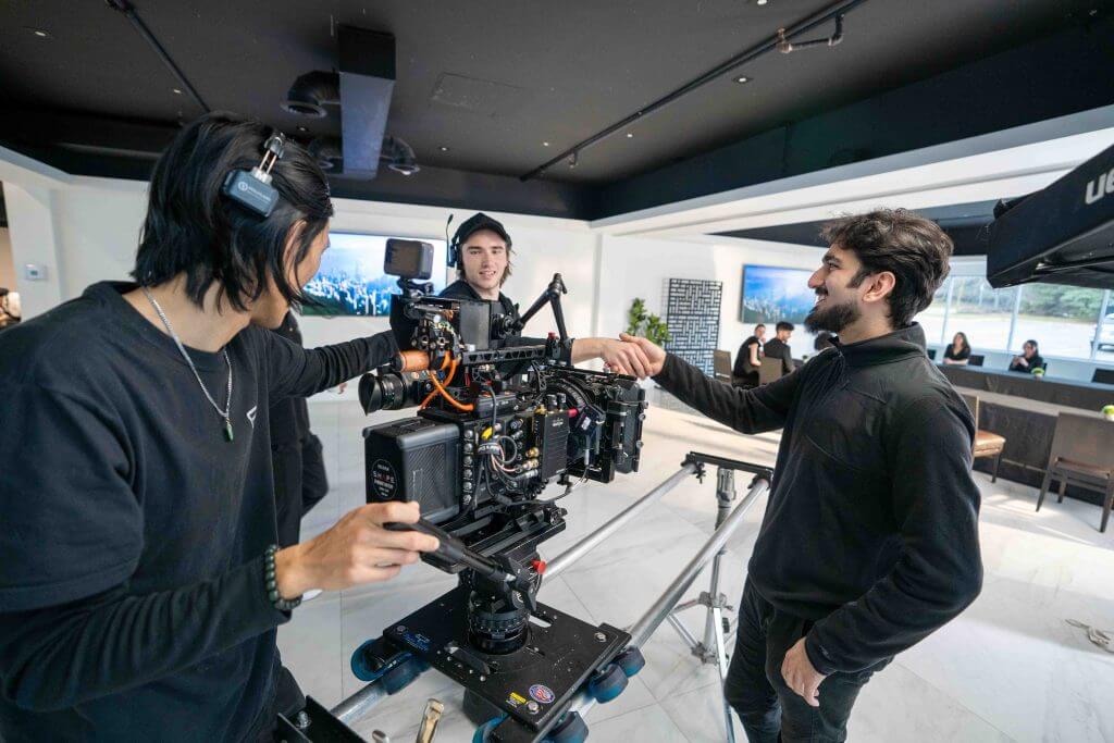 FX Productions Canada Three crew members adjust a professional video camera on set in a modern indoor space, preparing for a film shoot by FX Productions Canada. Toronto Video Production Company