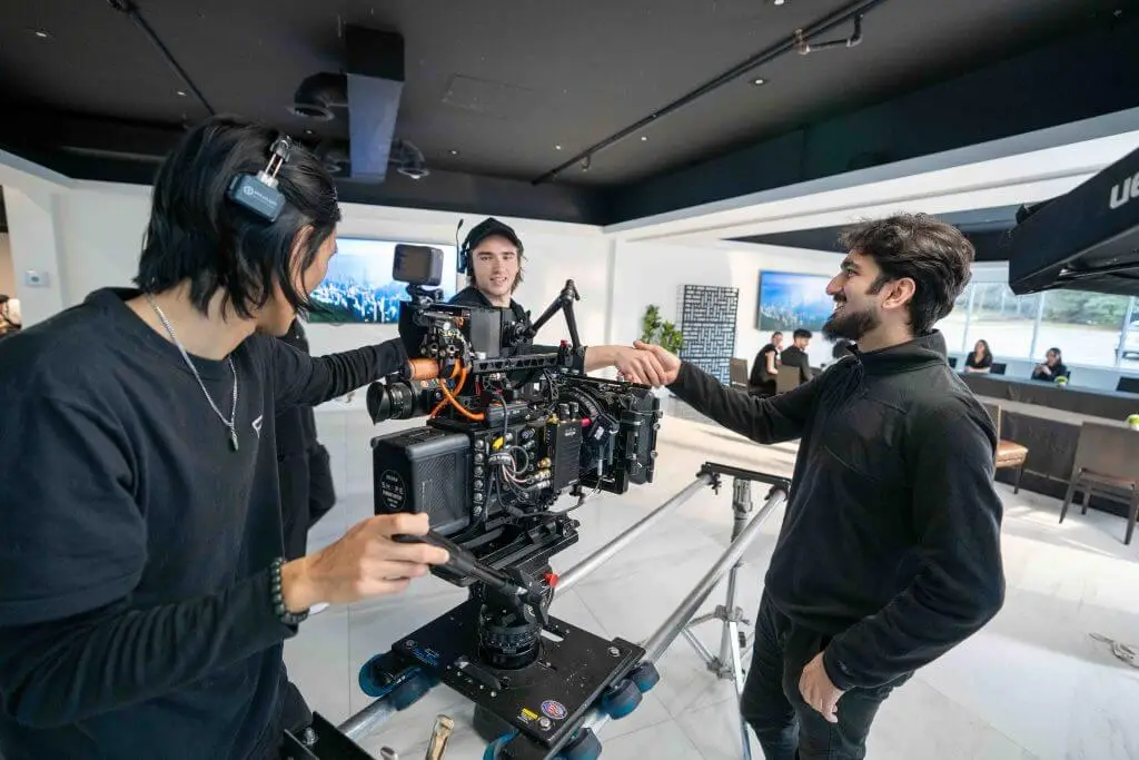FX Productions Canada Three crew members adjust a professional video camera on set in a modern indoor space, preparing for a film shoot by FX Productions Canada. Toronto Video Production Company