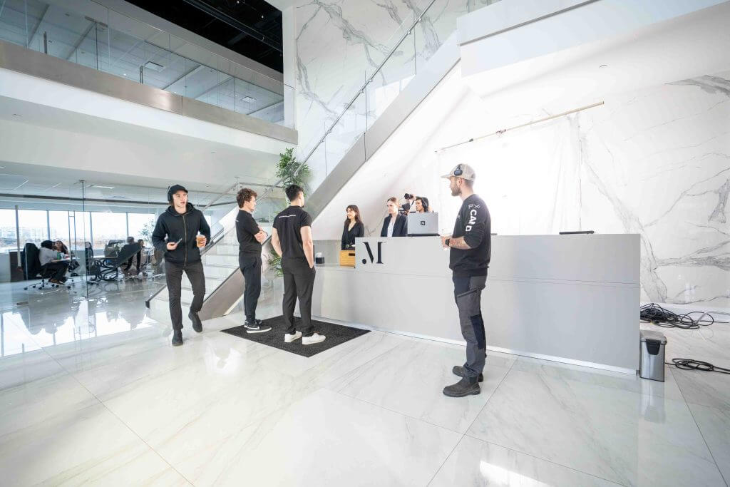 FX Productions Canada A group of people stand and talk near a modern white marble reception desk in a spacious, bright office lobby at FX Productions Canada, a leading Toronto production company. Toronto Video Production Company