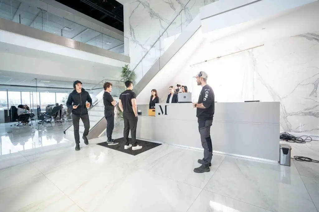 FX Productions Canada A group of people stand and talk near a modern white marble reception desk in a spacious, bright office lobby at FX Productions Canada, a leading Toronto production company. Toronto Video Production Company