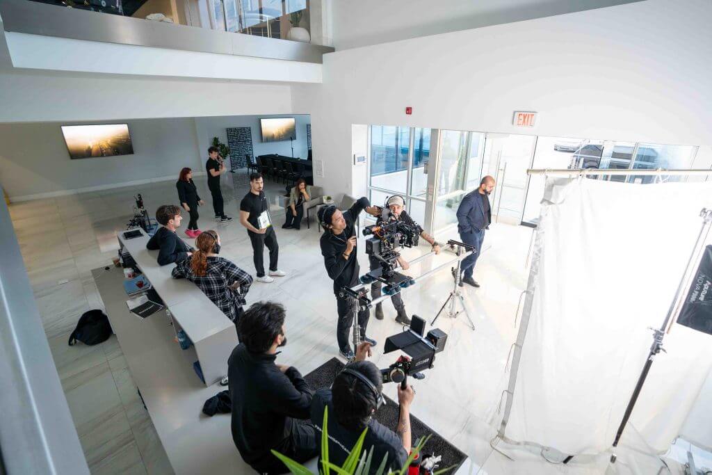 FX Productions Canada A Toronto Production Company film crew sets up cameras and lighting for a video shoot in a modern, white, open space with several people observing and working. Toronto Video Production Company