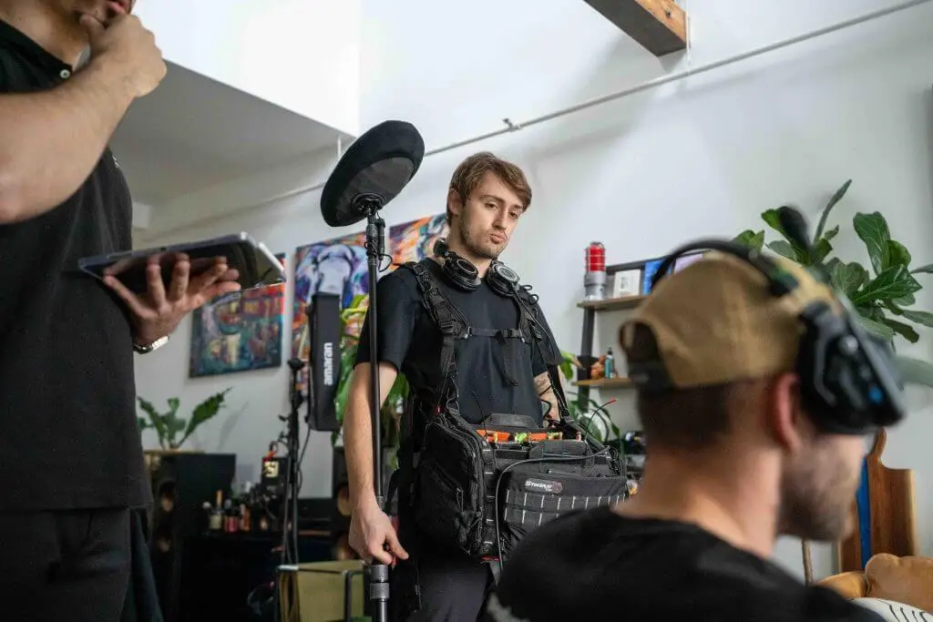 FX Productions Canada A sound technician wearing headphones and carrying audio equipment stands indoors at FX Productions Canada, while two other people with headsets work nearby for this Toronto Video Production. Toronto Video Production Company