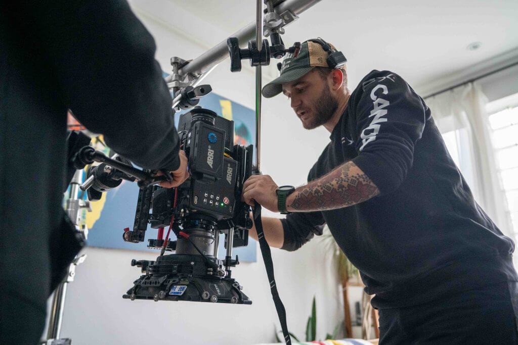 FX Productions Canada Two crew members from FX Productions Canada adjust a professional video camera mounted on a rig in a well-lit indoor setting. Toronto Video Production Company