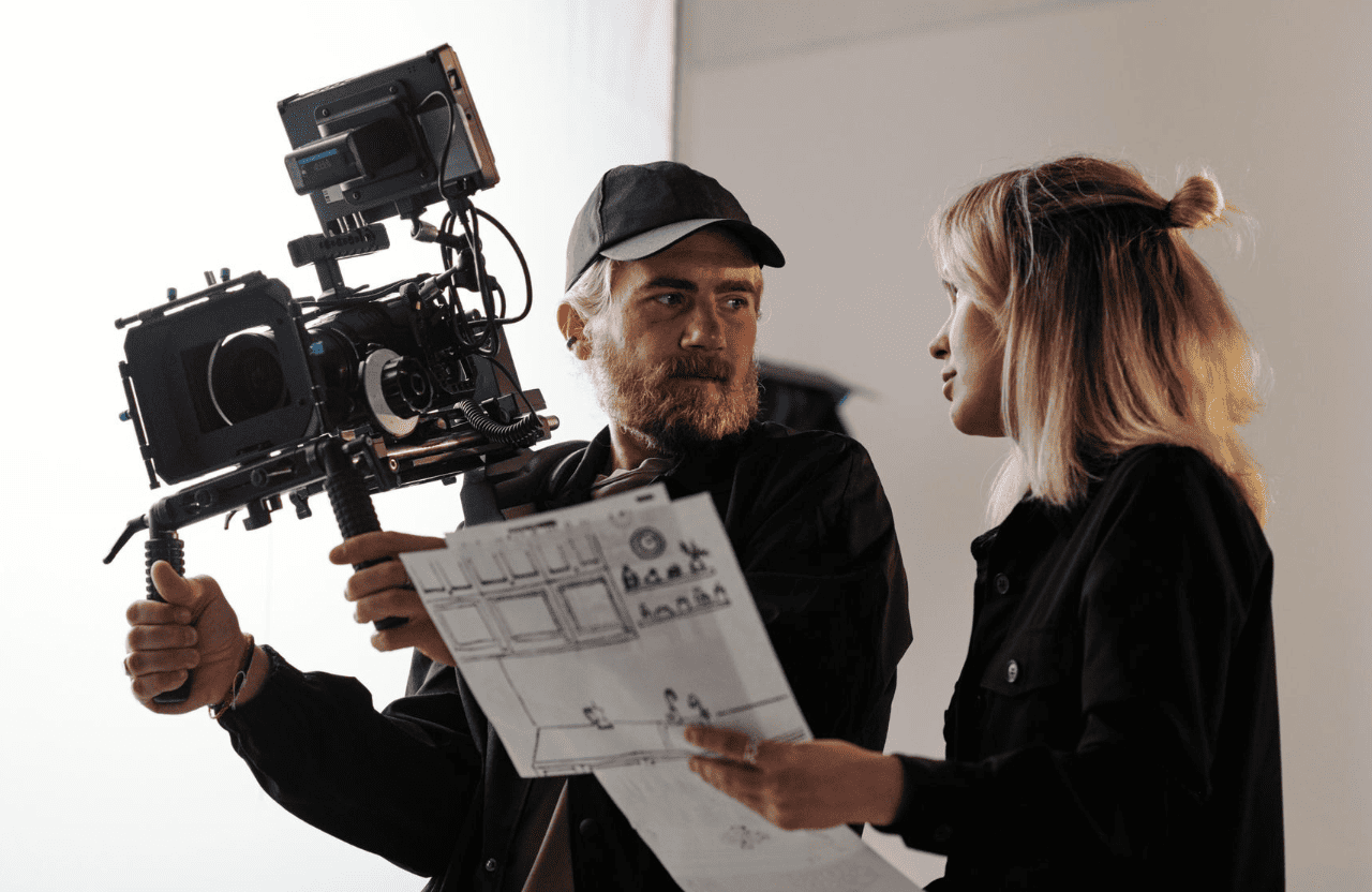 FX Productions Canada A man holding a professional video camera talks with a woman holding illustrated papers; they appear to be on a film set for FX Productions Canada. Toronto Video Production Company