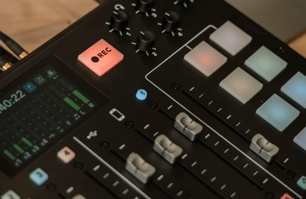 FX Productions Canada Close-up of an audio mixer with sliders, a digital display, illuminated control pads, and a glowing red REC button, highlighting the recording session at FX Productions Canada—a leading Toronto Production Company. Toronto Video Production Company
