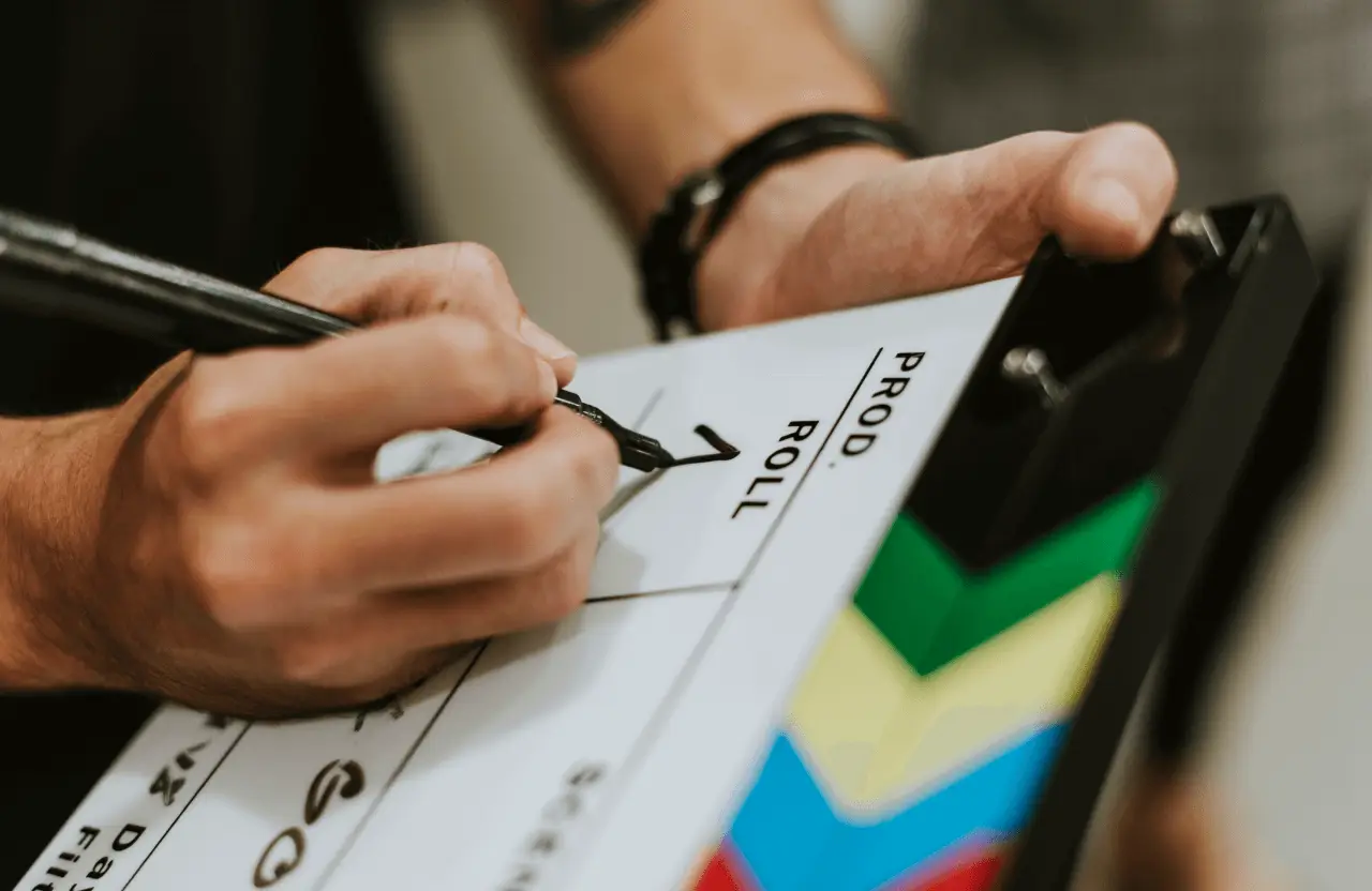 FX Productions Canada A person writes on a film clapperboard with a black marker, preparing it for a scene; colorful stripes line the side, showcasing the professional touch of FX Productions Canada. Toronto Video Production Company