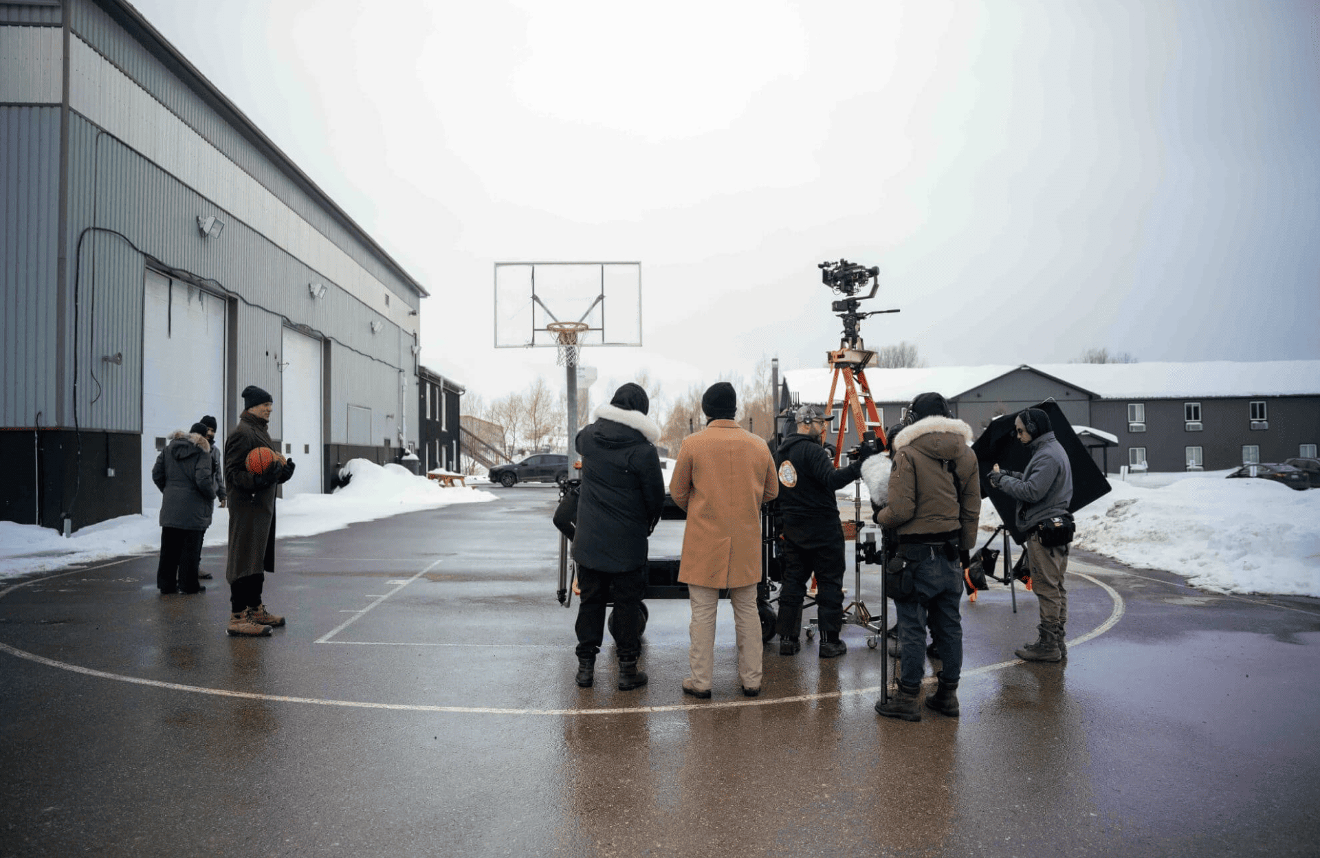 FX Productions Canada A Toronto Production Company sets up equipment on an outdoor basketball court in winter, with snow on the ground and buildings in the background. Toronto Video Production Company