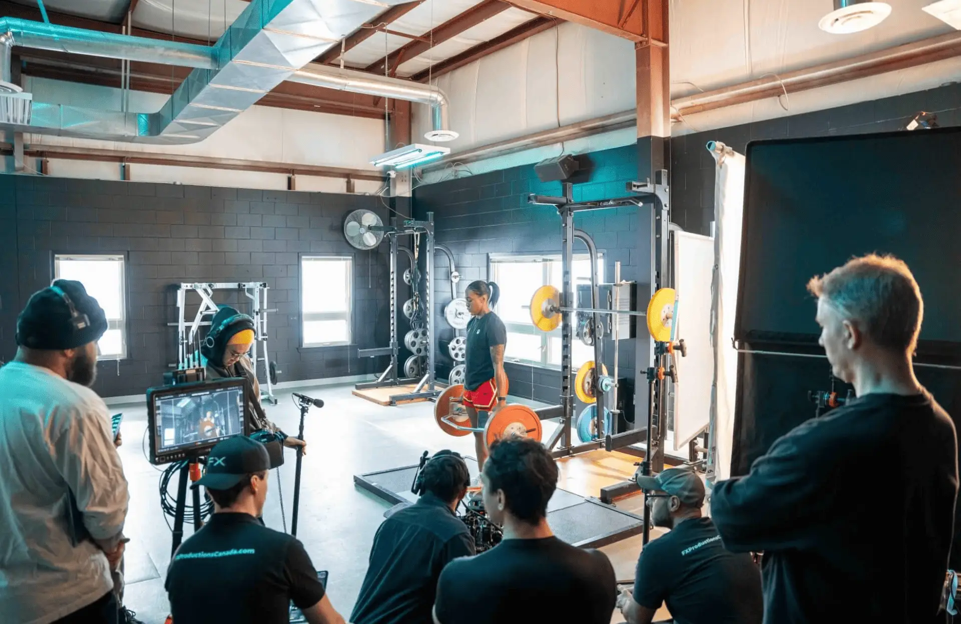 FX Productions Canada A Toronto Production Company captures a person lifting weights in a gym, with cameras, lighting equipment, and several FX Productions Canada crew members visible. Toronto Video Production Company