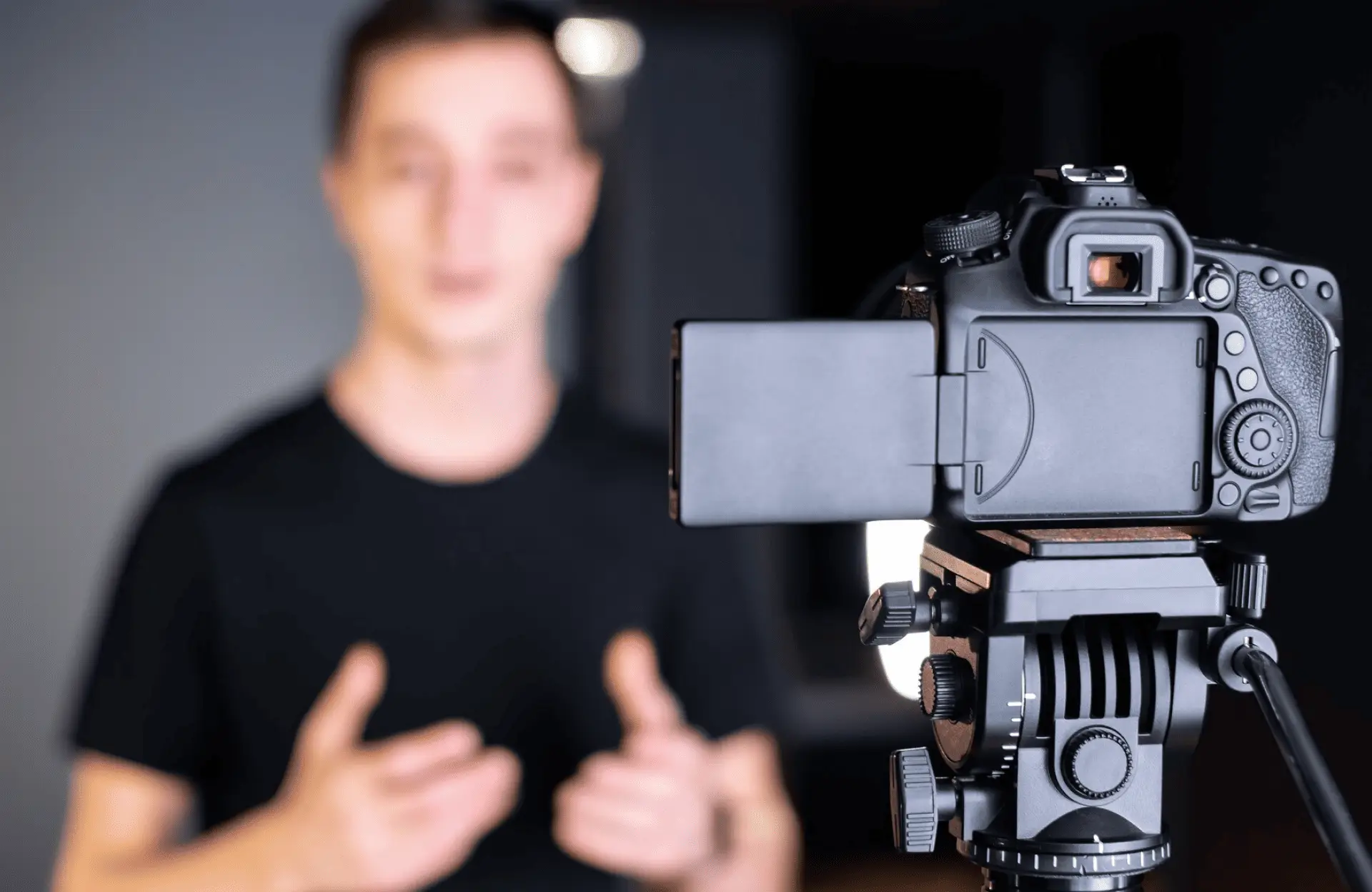 FX Productions Canada A digital camera on a tripod records a person in a black shirt speaking with hand gestures, who appears out of focus in the background. Toronto Video Production Company