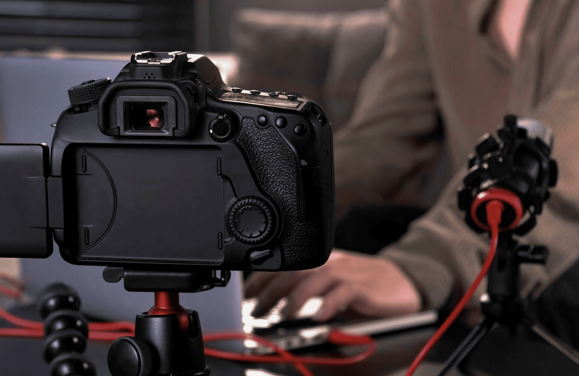 FX Productions Canada A digital camera on a tripod records a person typing on a laptop, with a microphone and red cables visible on the desk. Toronto Video Production Company
