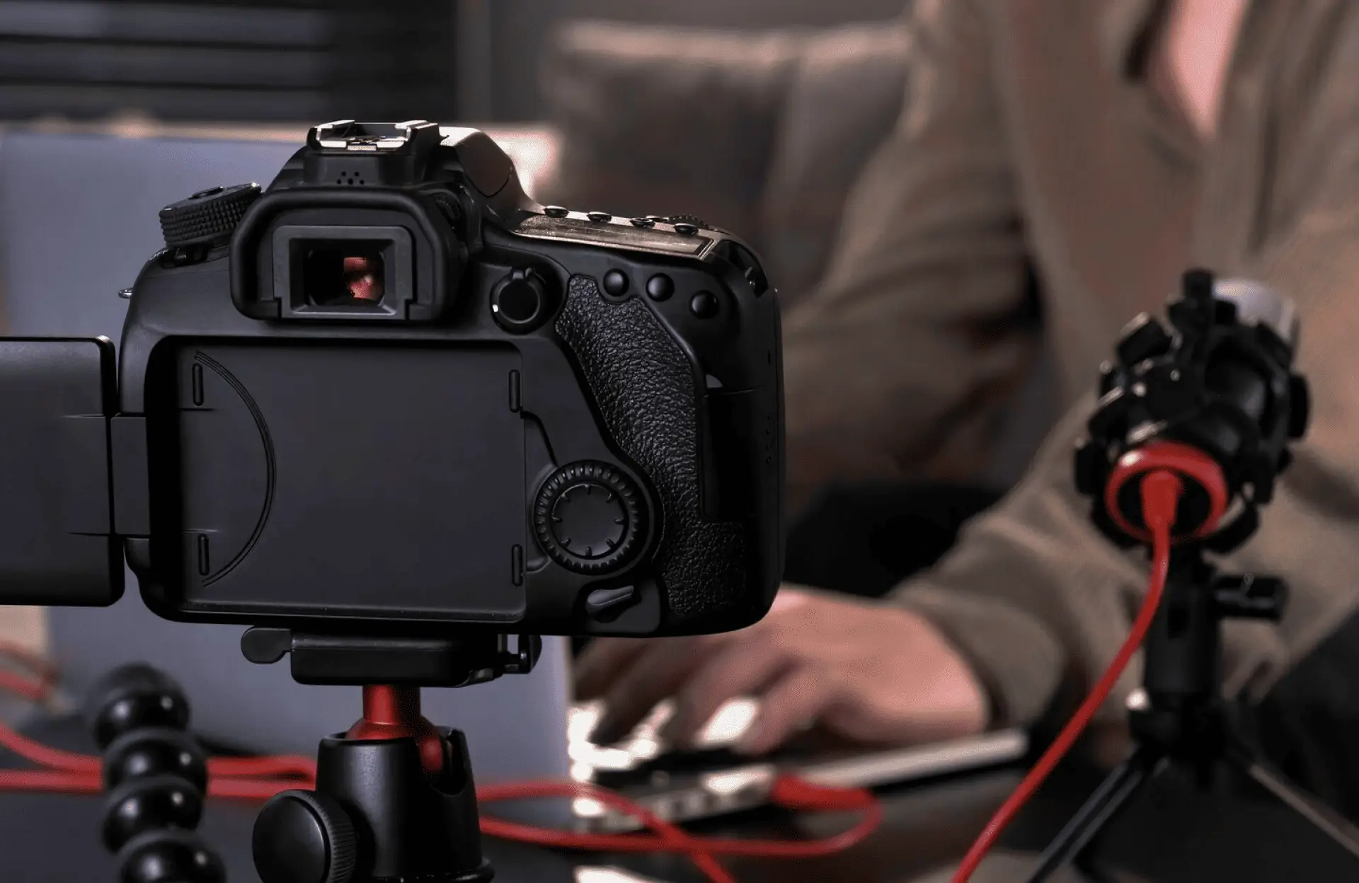 FX Productions Canada A digital camera on a tripod records a person typing on a laptop, with a microphone and red cables visible on the desk. Toronto Video Production Company