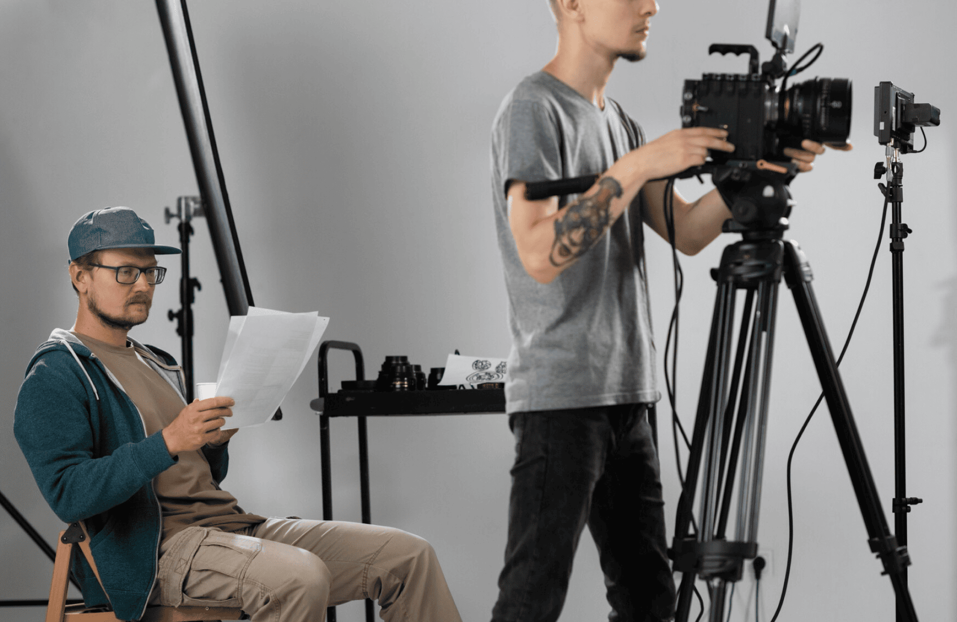FX Productions Canada Two men work in a film studio; one sits reading papers while the other stands operating a professional video camera on a tripod. Toronto Video Production Company