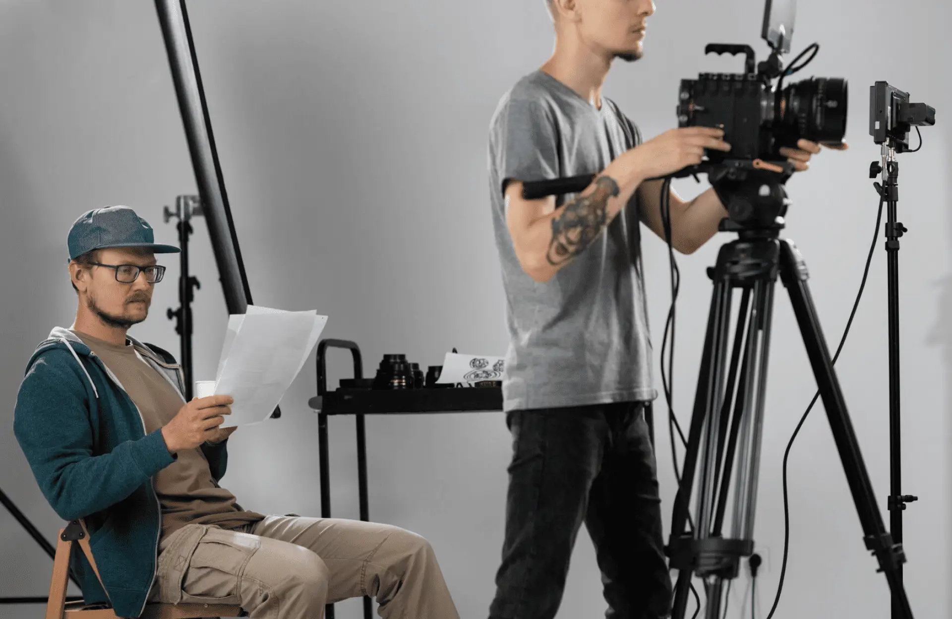 FX Productions Canada Two men work in a film studio; one sits reading papers while the other stands operating a professional video camera on a tripod. Toronto Video Production Company