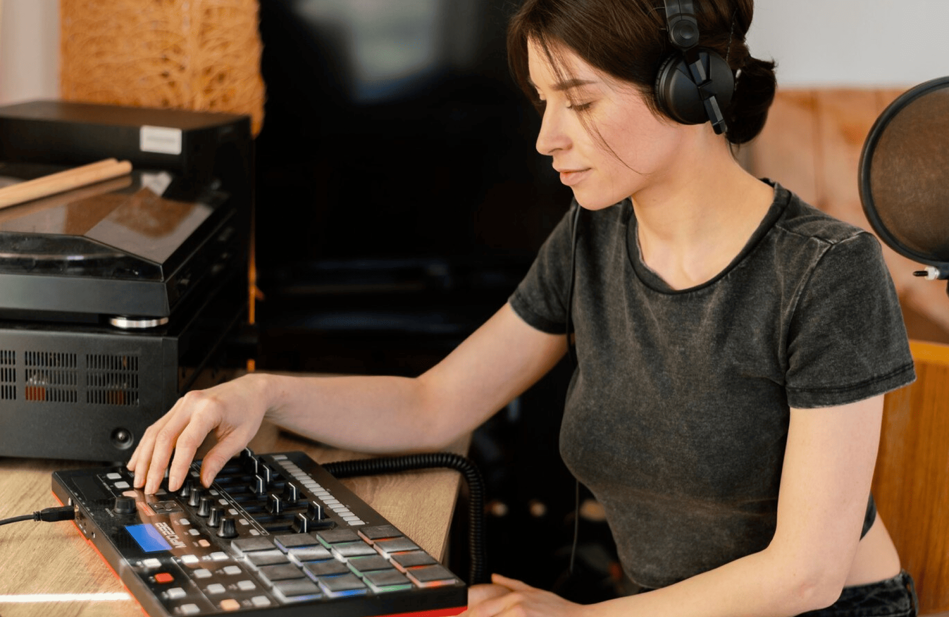 FX Productions Canada A woman wearing headphones operates a music production controller at a desk in a home studio setting. Toronto Video Production Company
