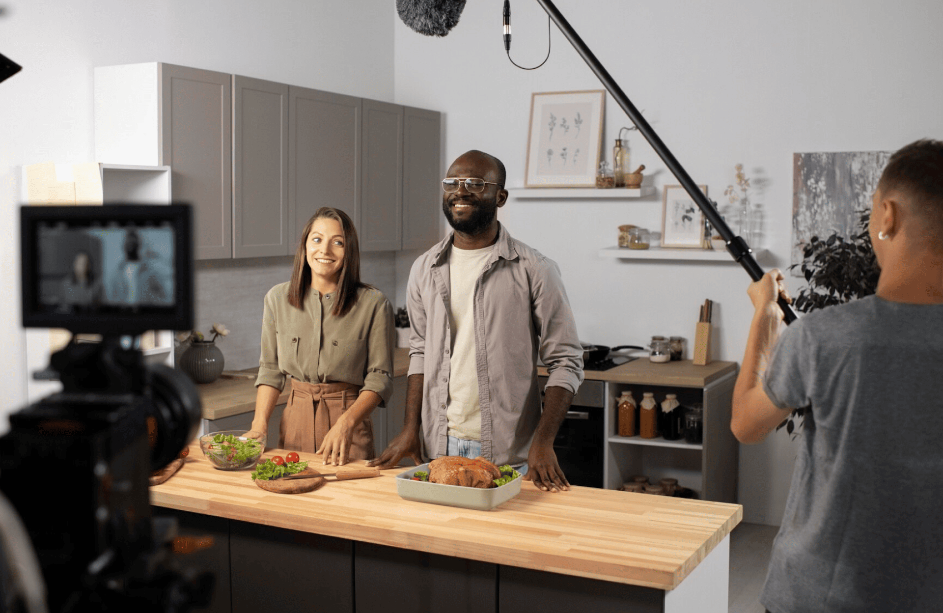 FX Productions Canada Two people stand behind a kitchen island with food, smiling at a camera while a film crew records them with a video camera and a boom microphone. Toronto Video Production Company