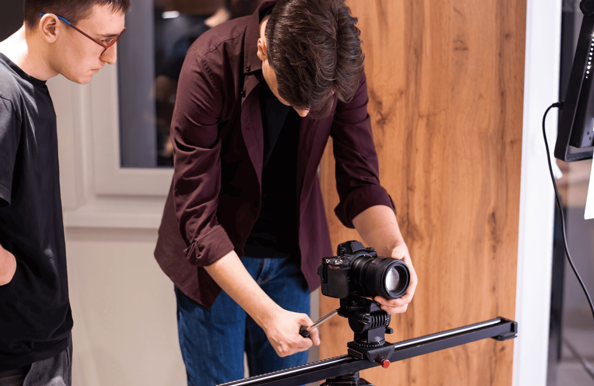 FX Productions Canada Two people set up a professional camera on a slider, with one person adjusting the camera and the other observing in a well-lit indoor setting. Toronto Video Production Company