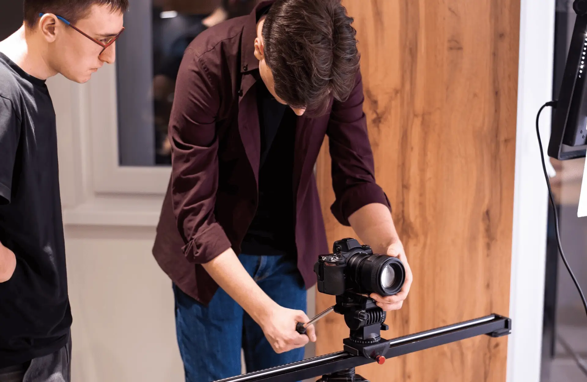 FX Productions Canada Two people set up a professional camera on a slider, with one person adjusting the camera and the other observing in a well-lit indoor setting. Toronto Video Production Company