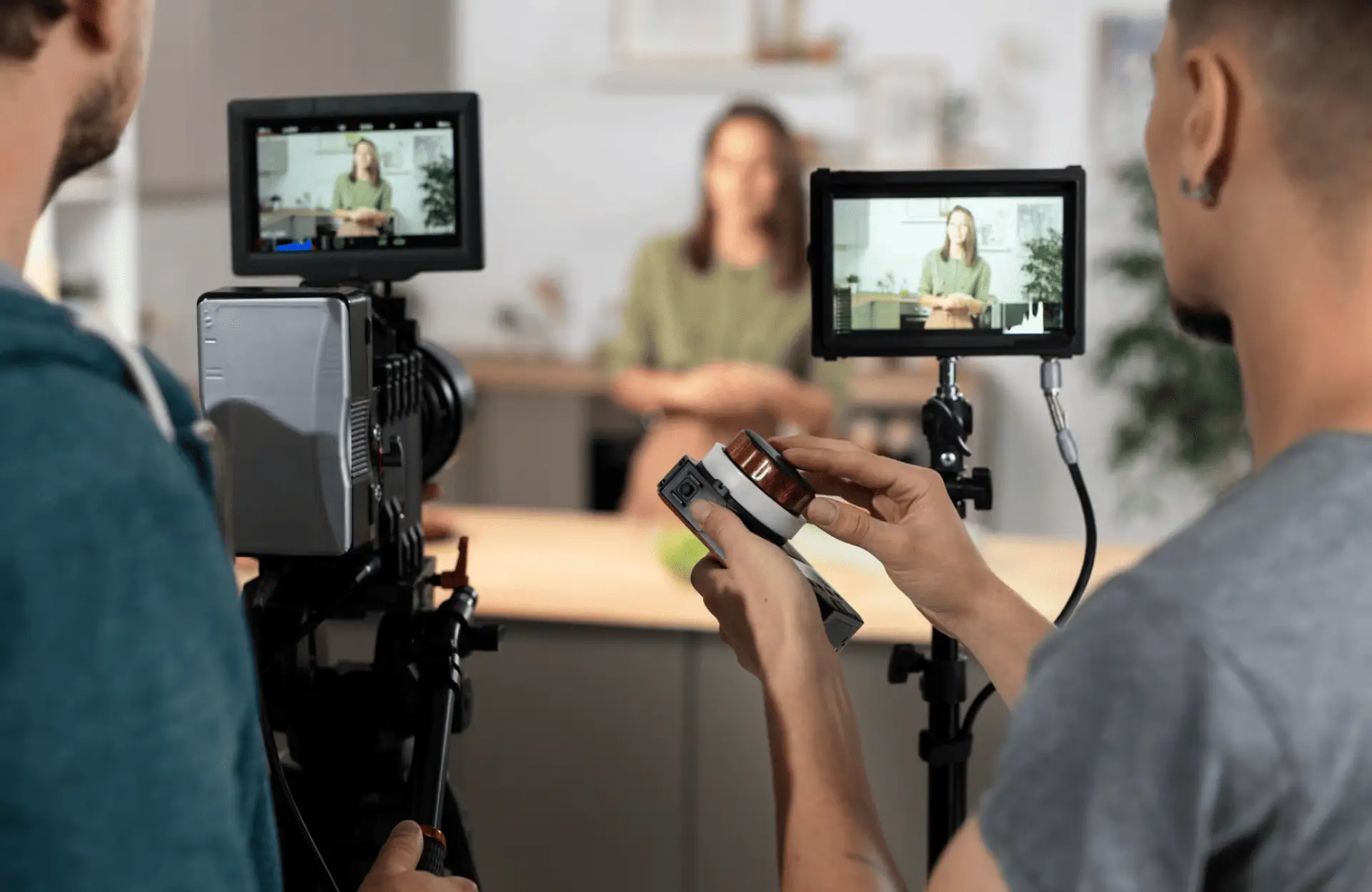 FX Productions Canada Two crew members operate cameras and monitors while filming a person sitting at a table in a studio setting. Toronto Video Production Company