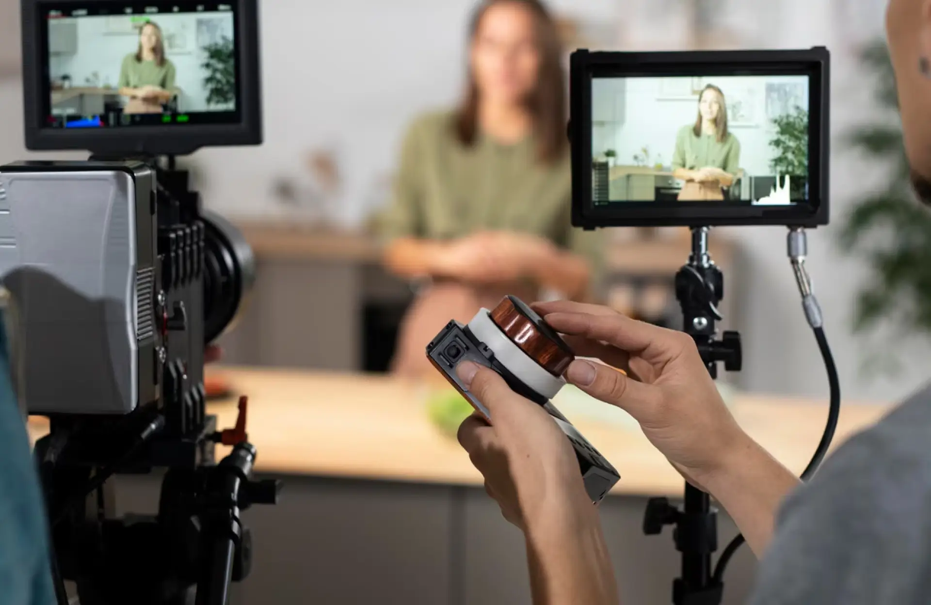 FX Productions Canada A person adjusts camera settings during a video recording session, with a woman speaking in front of the camera and her image visible on two monitor screens. Toronto Video Production Company