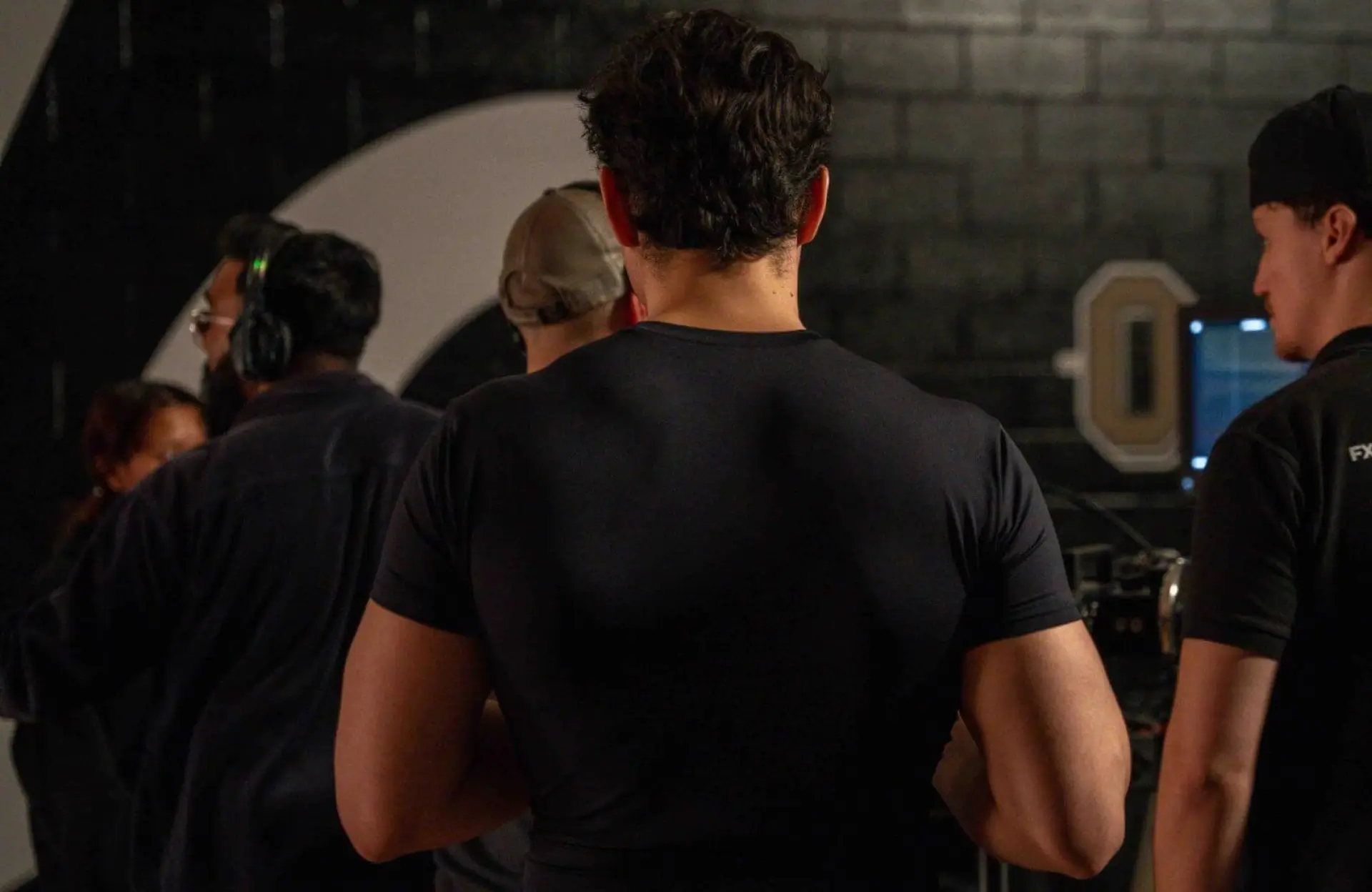 FX Productions Canada Several people stand indoors with their backs to the camera, facing a dark wall and some equipment. Toronto Video Production Company