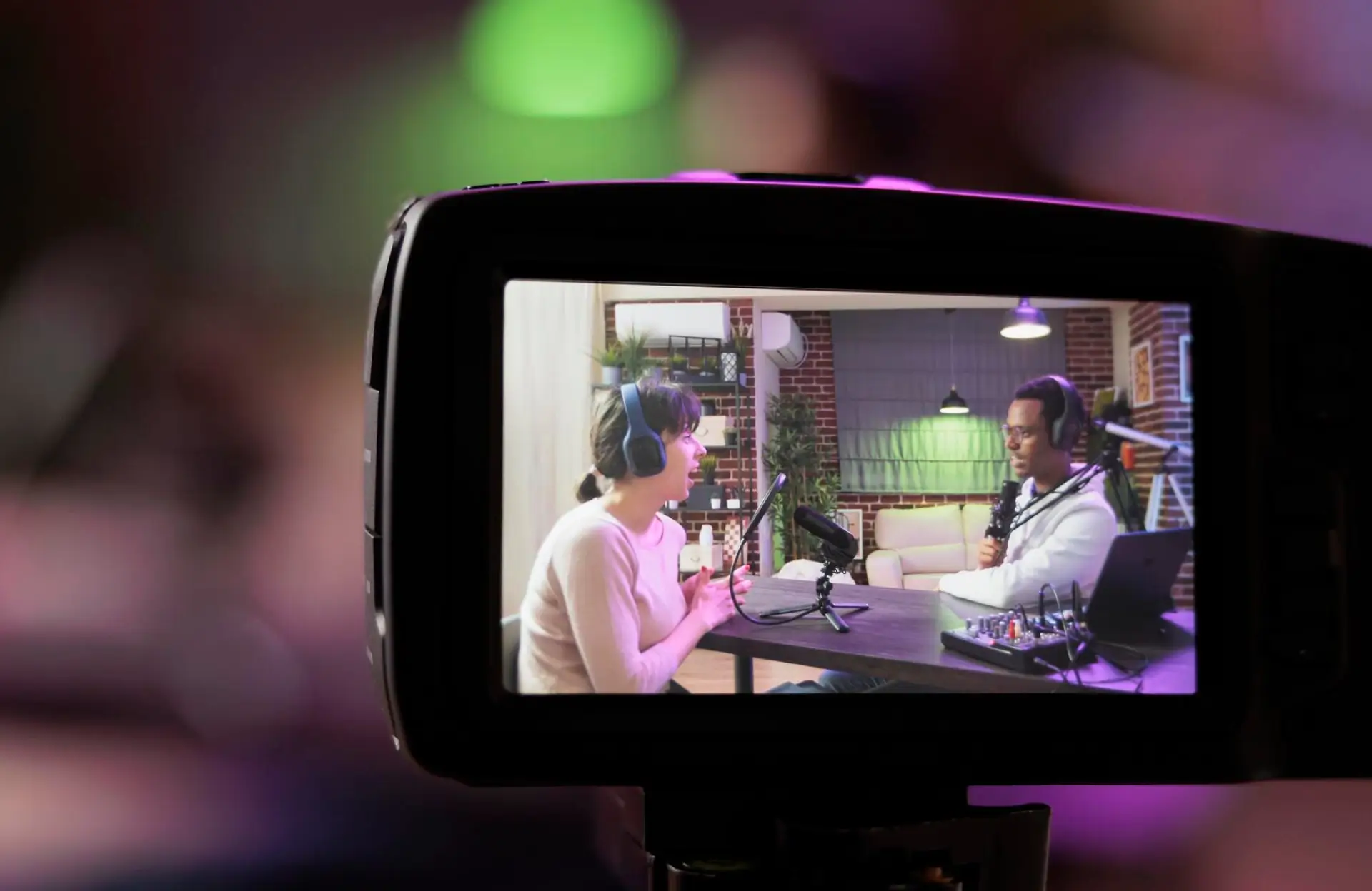 FX Productions Canada A camera screen displays two people wearing headphones and speaking into microphones in a podcast recording studio. Toronto Video Production Company