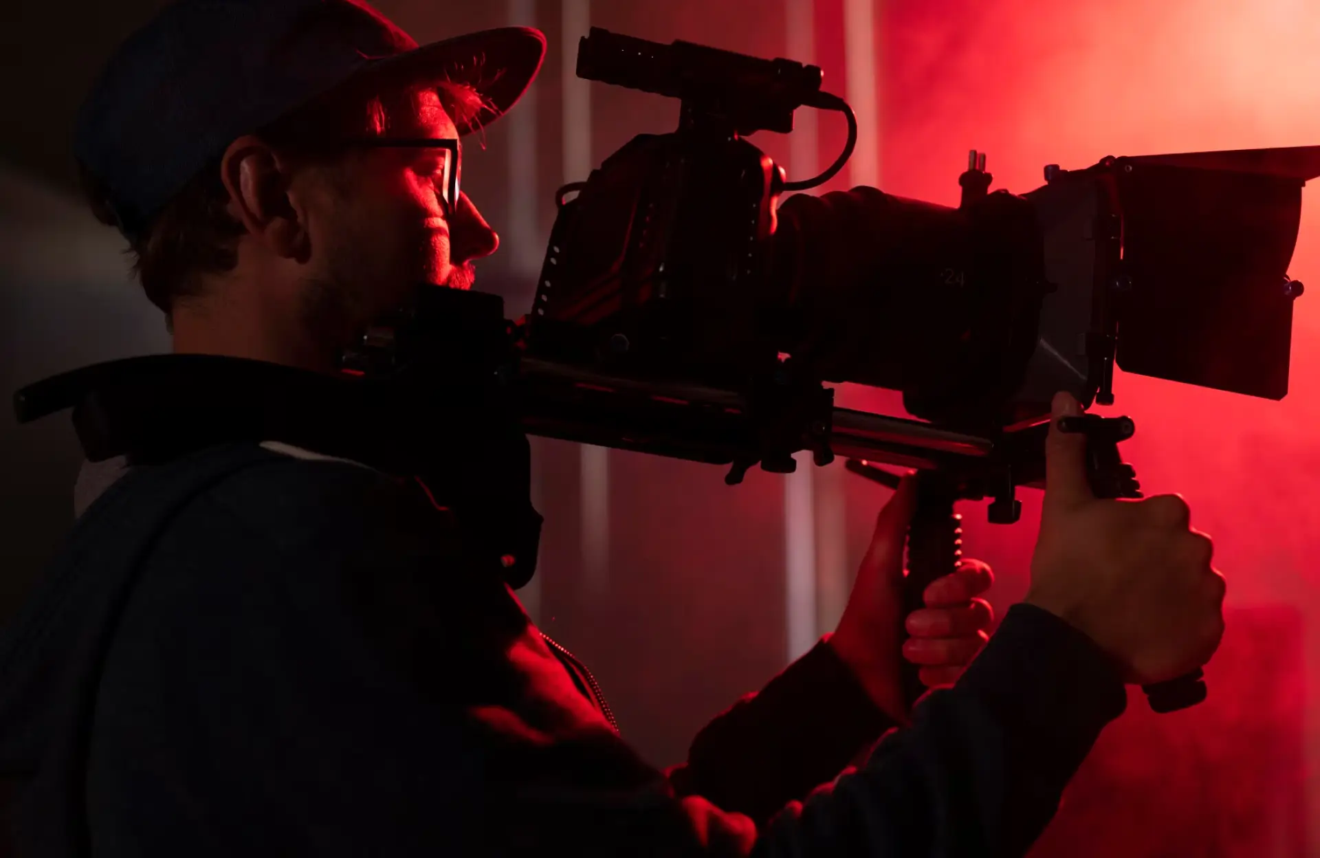 FX Productions Canada Person operating a professional video camera rig in a dimly lit environment with red lighting. Toronto Video Production Company