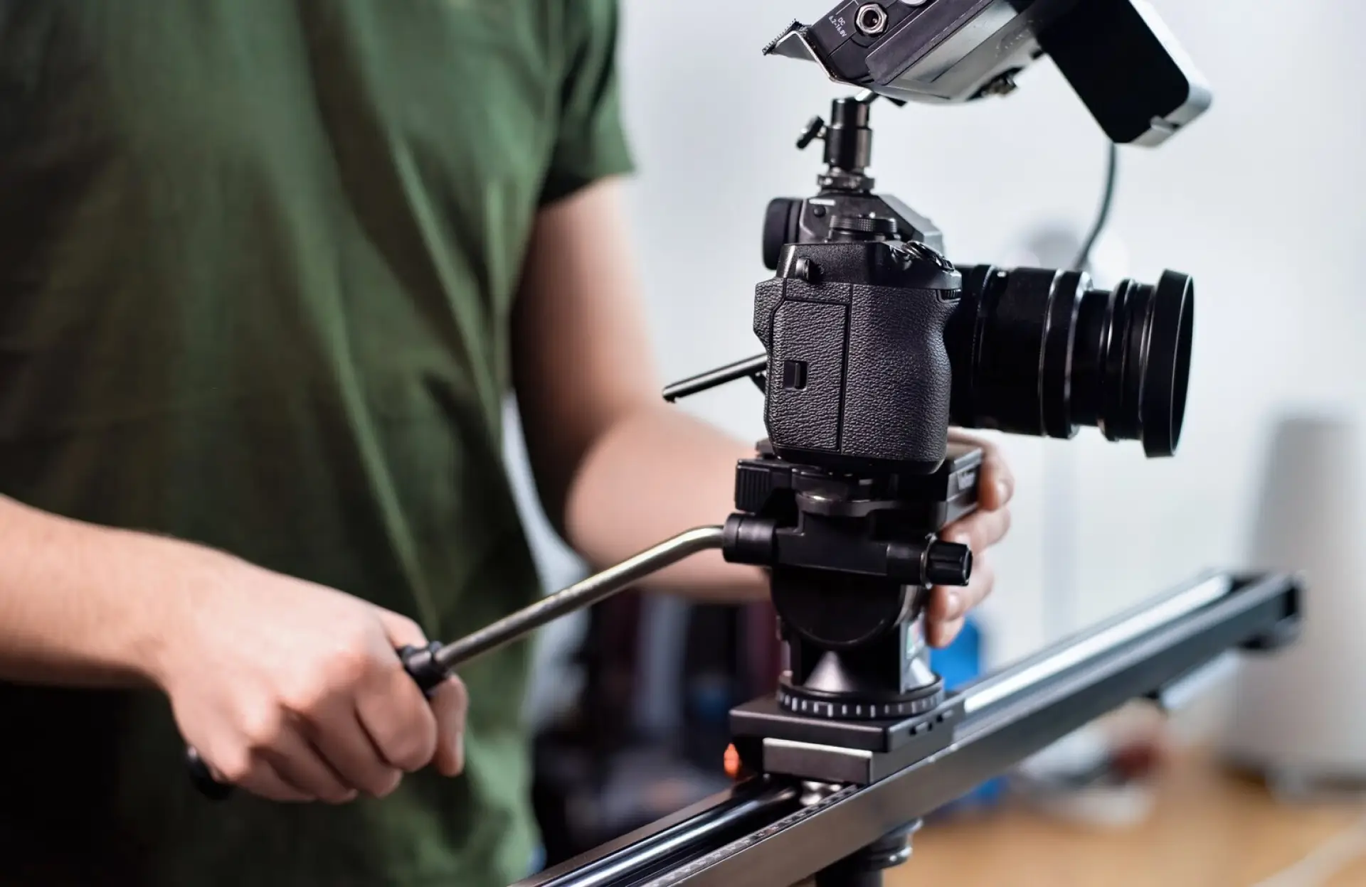 FX Productions Canada Person operating a professional video camera mounted on a tripod with a slider, adjusting the camera position. Toronto Video Production Company