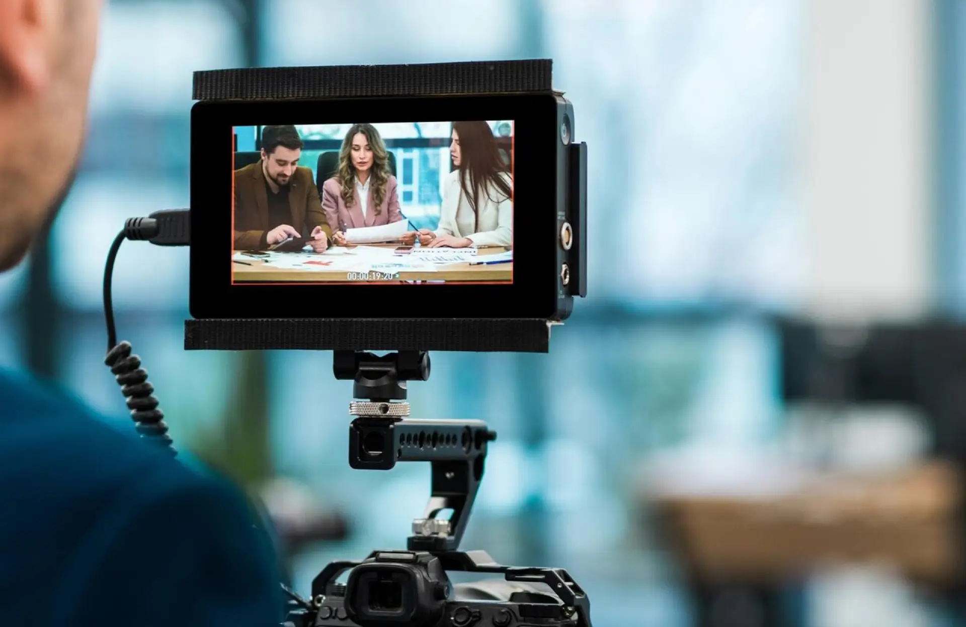 FX Productions Canada A camera's display shows three people sitting at a table and discussing documents in a bright, modern office setting. Toronto Video Production Company