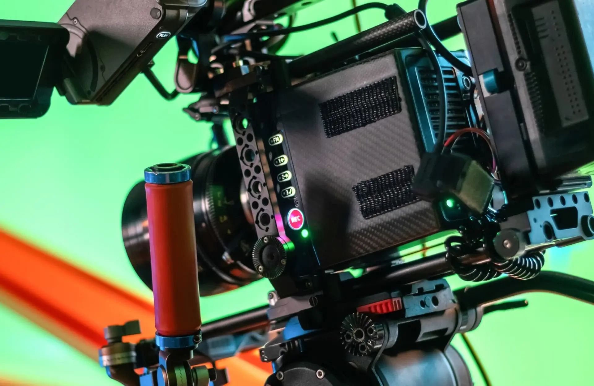 FX Productions Canada Close-up of a professional video camera with various buttons, controls, and a red handle, set against a green screen background. Toronto Video Production Company