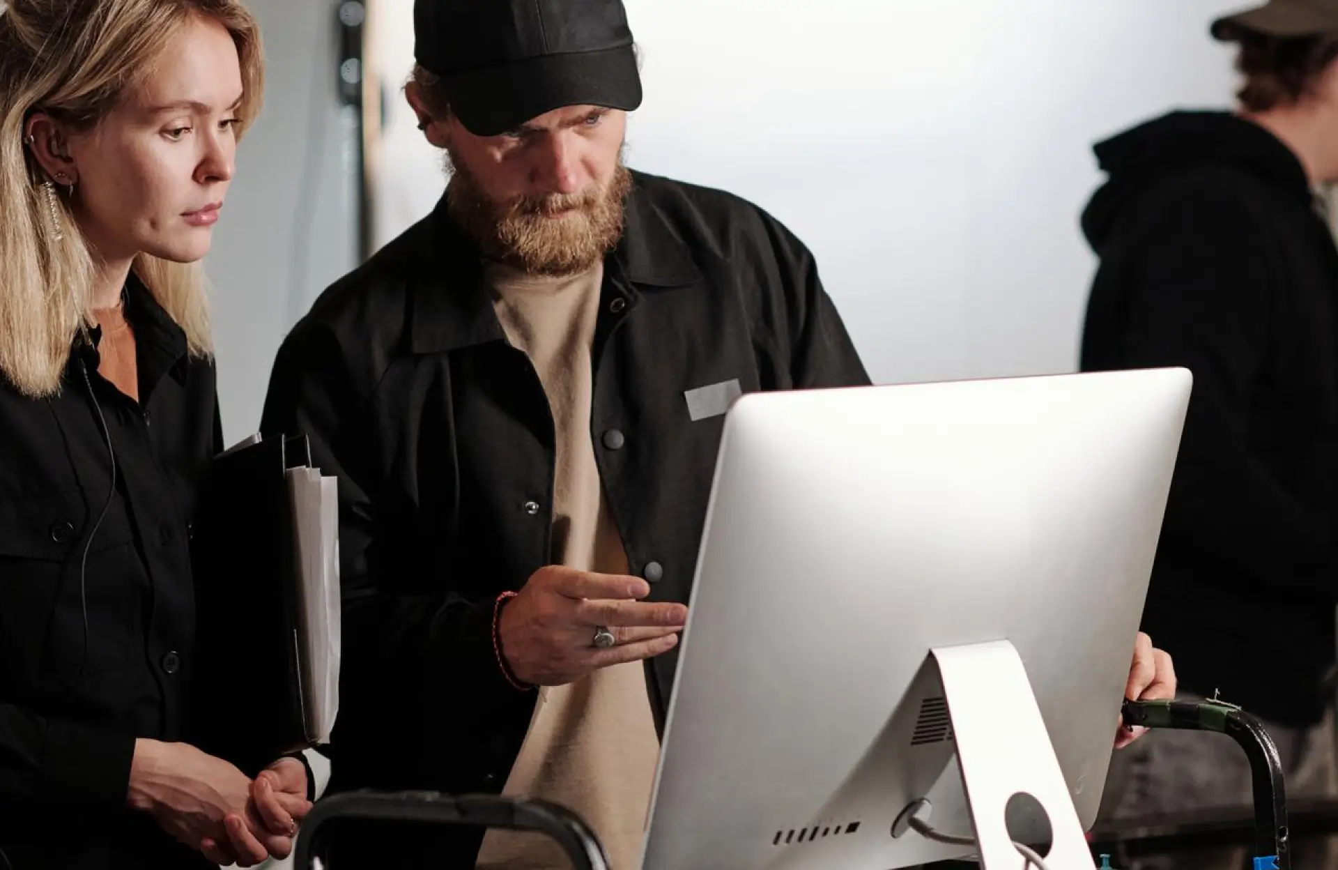 FX Productions Canada Two people stand in front of a desktop computer, reviewing something on the screen; one holds documents and the other points at the monitor. Toronto Video Production Company