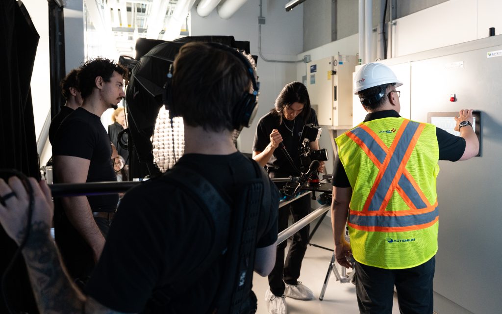FX Productions Canada A film crew records a worker in a white hard hat and safety vest operating equipment in an industrial setting. Toronto Video Production Company