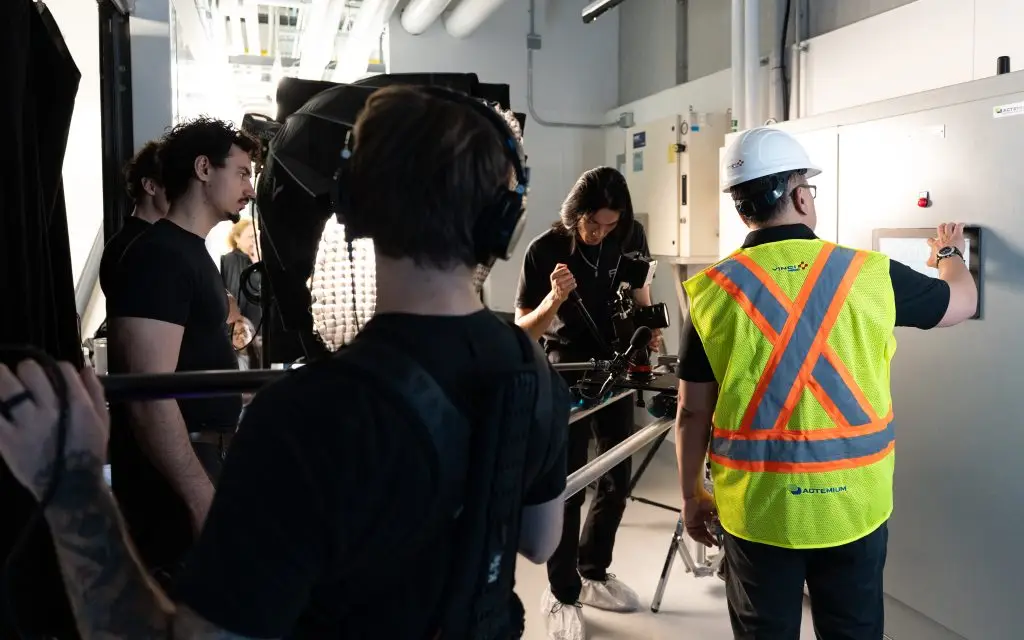 FX Productions Canada A film crew records a worker in a white hard hat and safety vest operating equipment in an industrial setting. Toronto Video Production Company