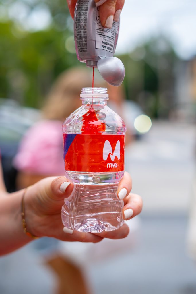 FX Productions Canada A person squeezes red Mio liquid water enhancer into a clear plastic water bottle outdoors. Toronto Video Production Company