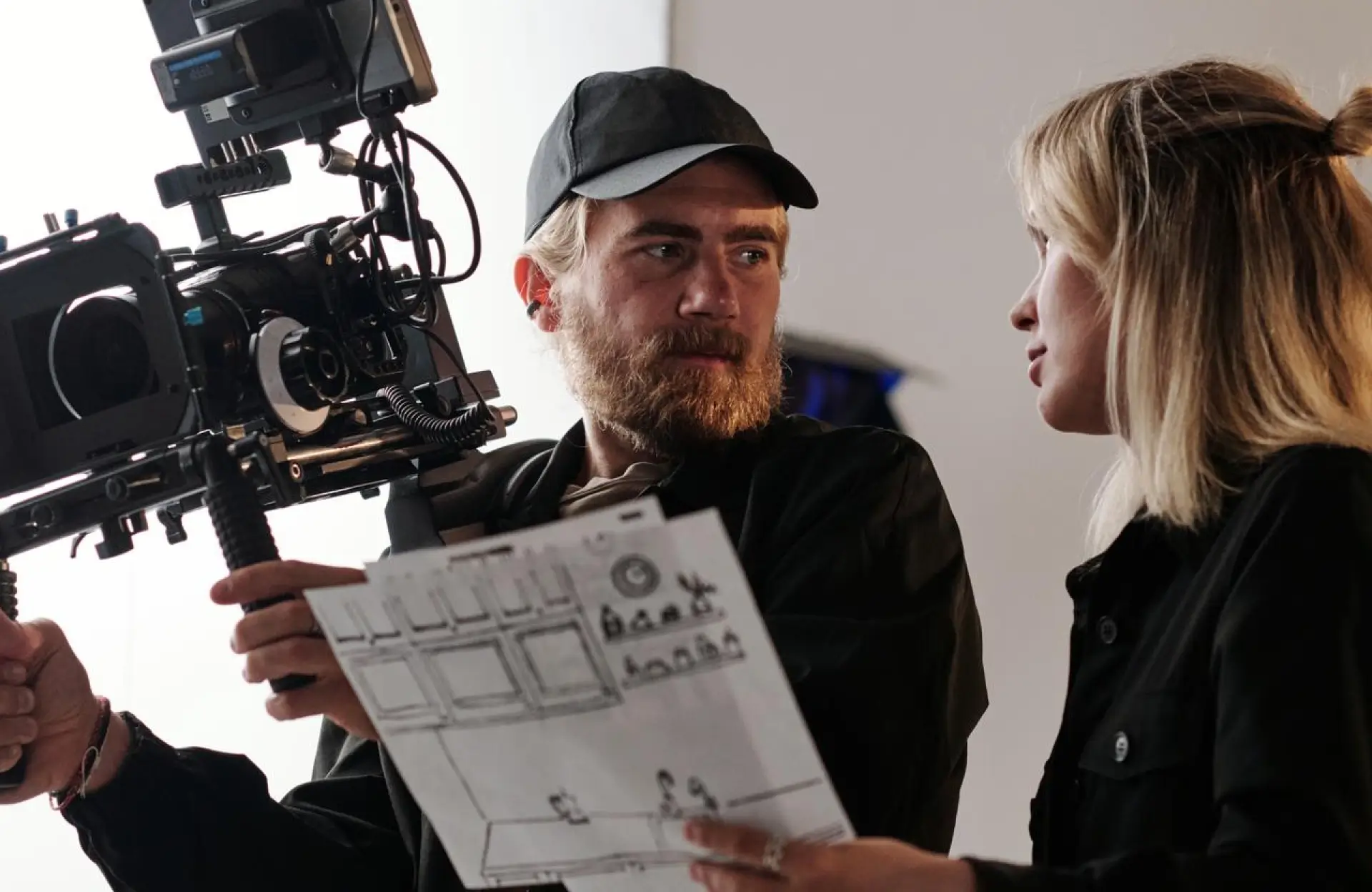 FX Productions Canada A man operates a professional film camera while holding a storyboard, speaking with a woman next to him on a film set. Toronto Video Production Company