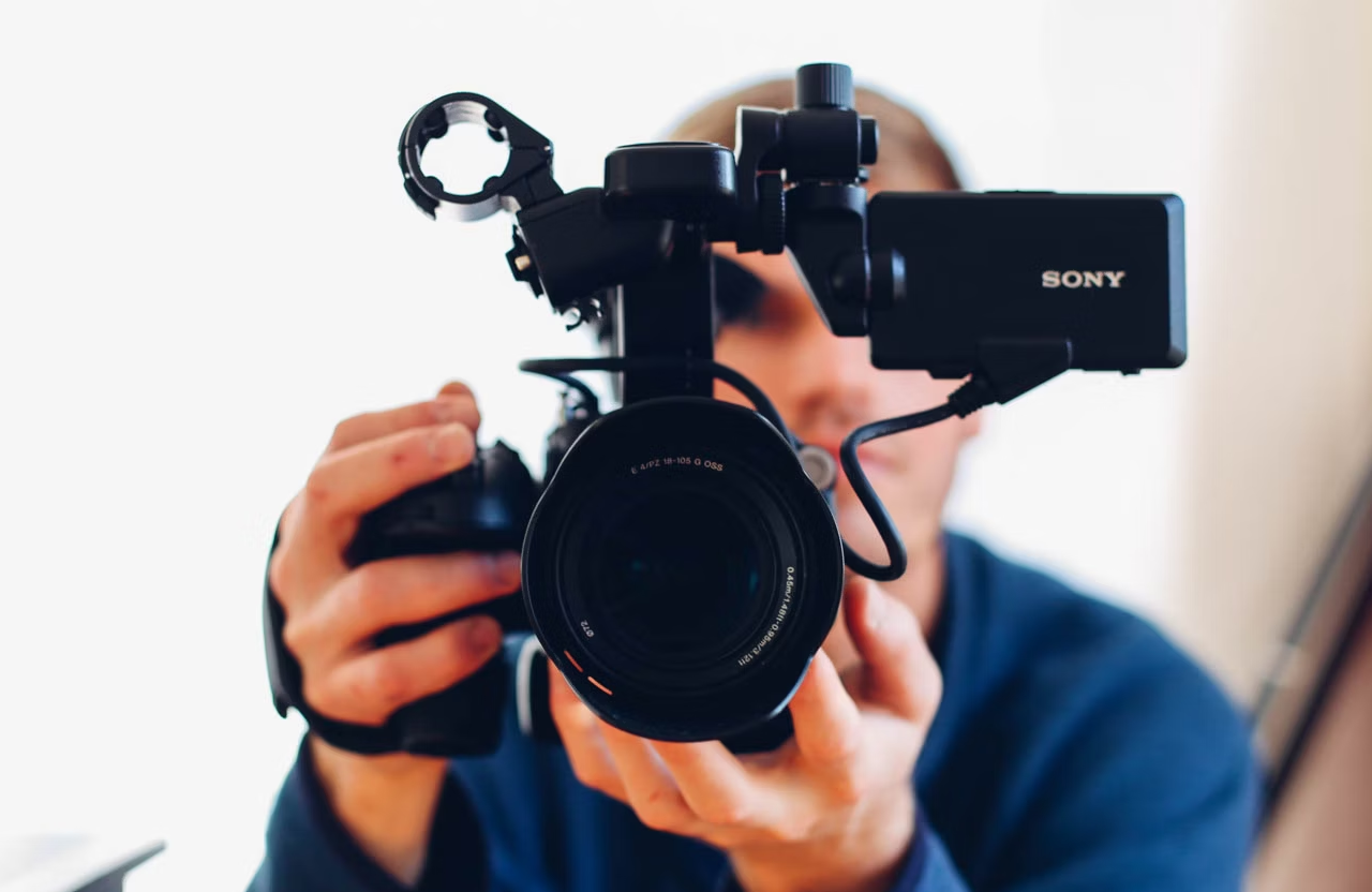 FX Productions Canada A person holds a professional Sony video camera, facing directly toward the lens, with the background out of focus—perfect for a video marketing agency creating branded videos. Toronto Video Production Company