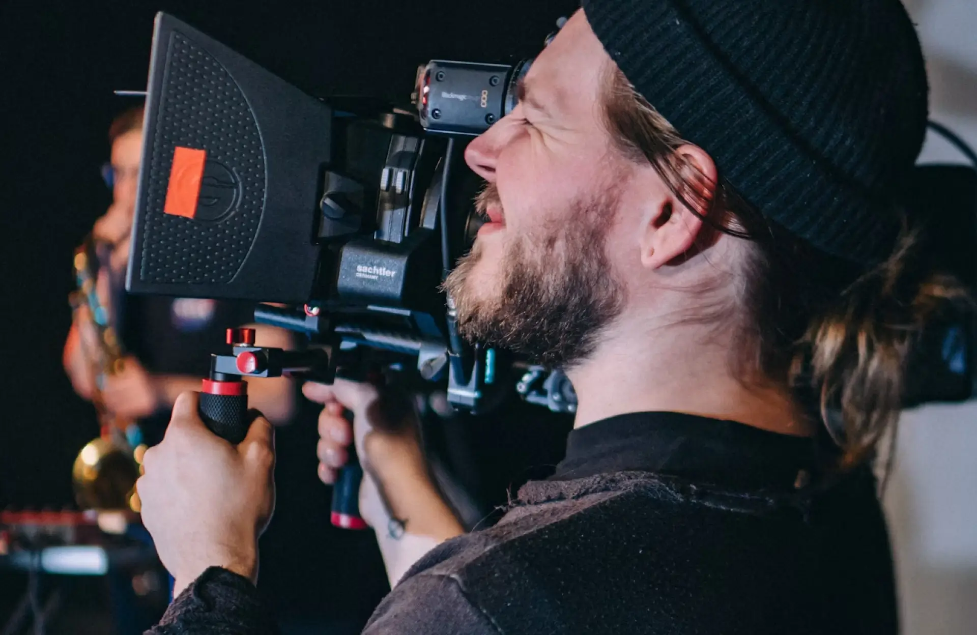 FX Productions Canada A person wearing a beanie operates a professional video camera, looking through the viewfinder while filming indoors. Toronto Video Production Company