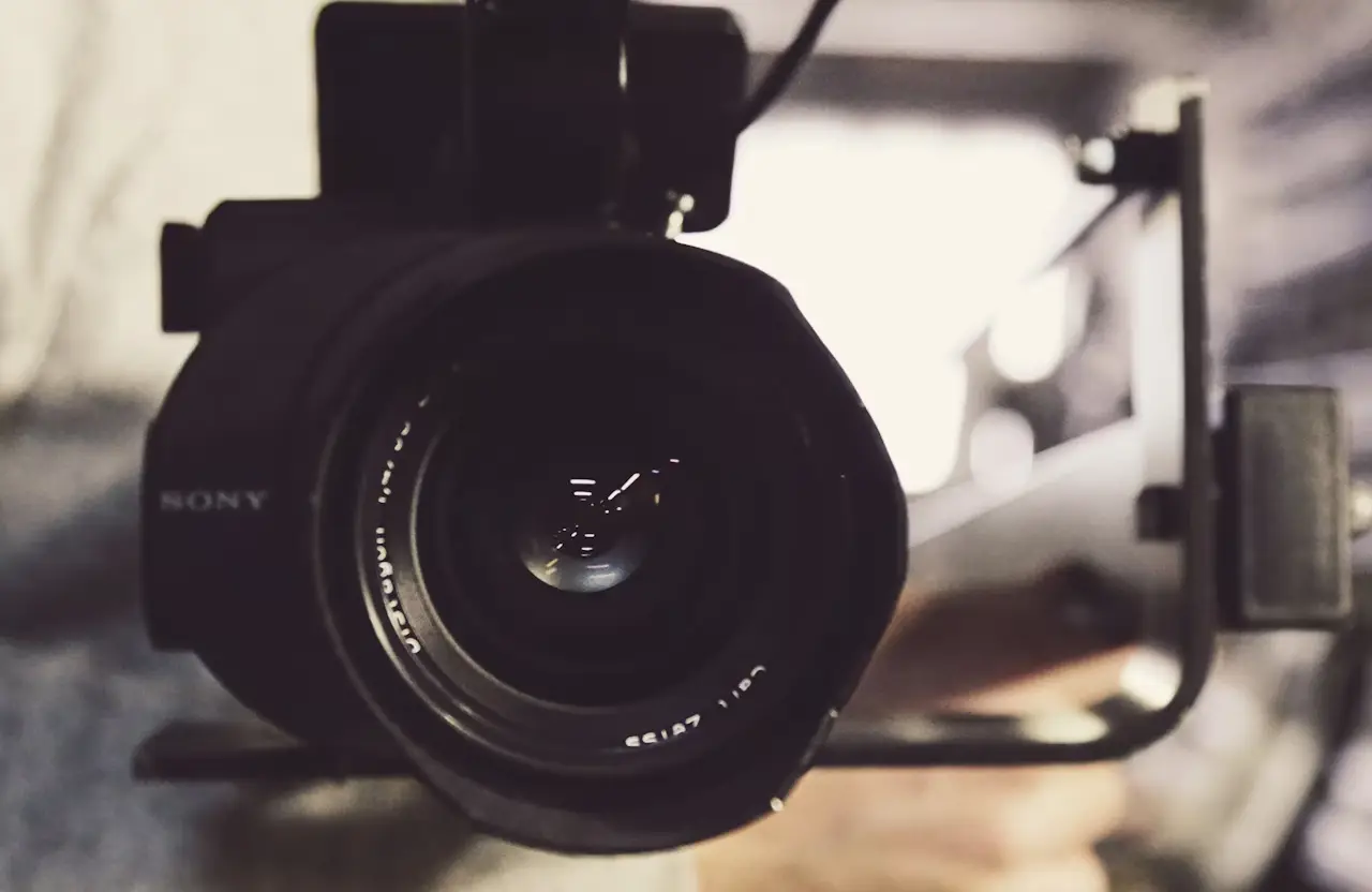 FX Productions Canada Close-up view of a professional Sony video camera lens, with blurred background and a person’s hand holding the camera rig—perfect for a video production company focused on cinematic storytelling to elevate your brand. Toronto Video Production Company