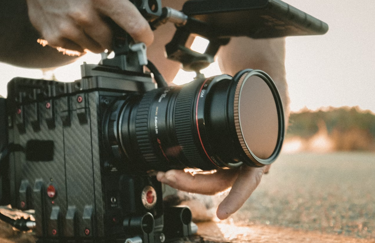 FX Productions Canada Close-up of a person adjusting a professional video camera outdoors with warm sunlight in the background, capturing the dynamic work often seen at top creative agencies Toronto is known for. Toronto Video Production Company
