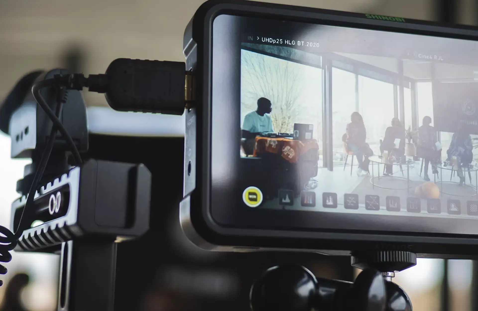 FX Productions Canada A camera monitor displays a live recording of several people seated and talking indoors, with daylight visible through large windows in the background. Toronto Video Production Company