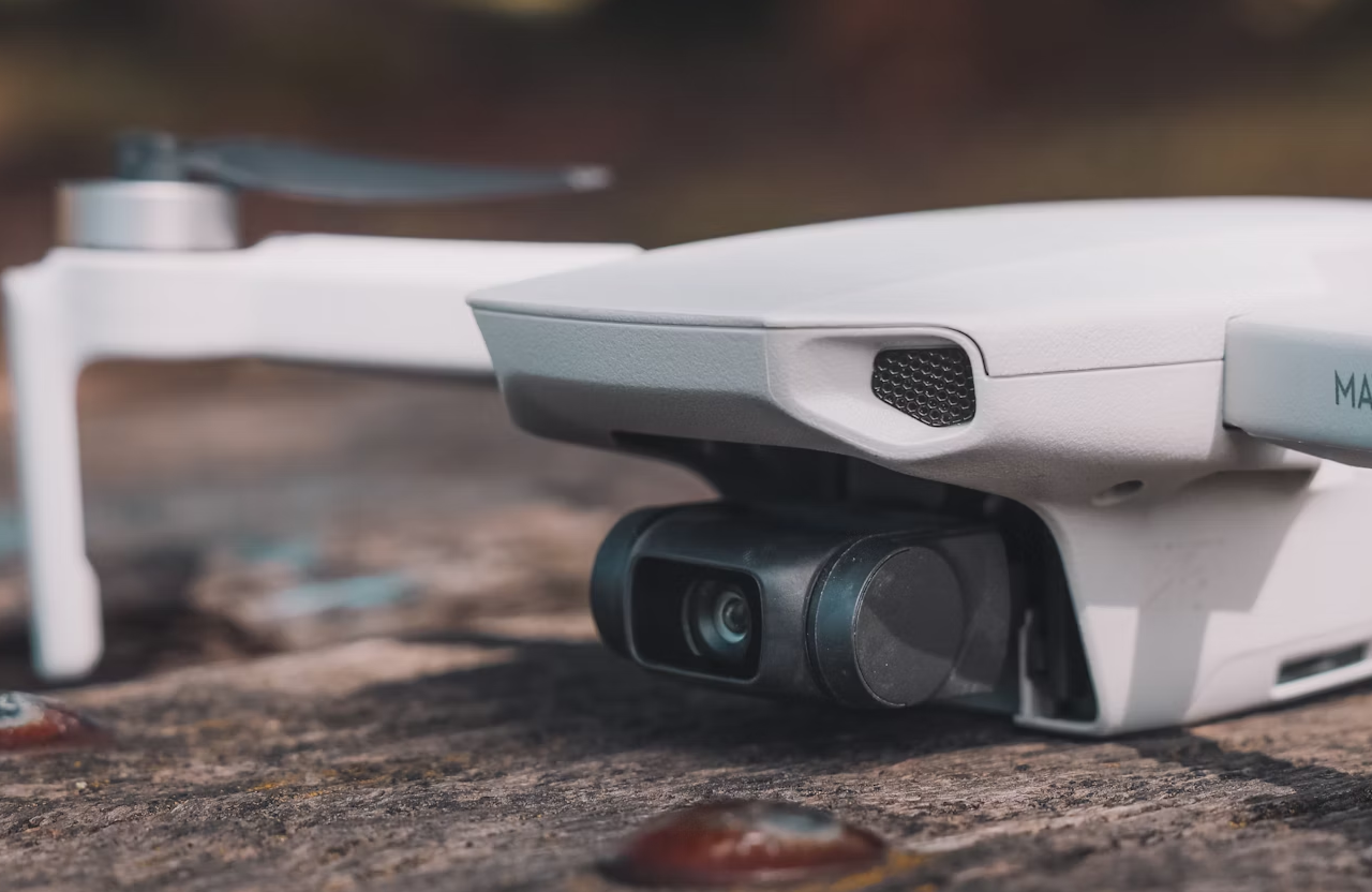 FX Productions Canada A close-up view of a white drone resting on a wooden surface, focusing on its camera and rotor arm—an essential tool for aerial video production. Toronto Video Production Company