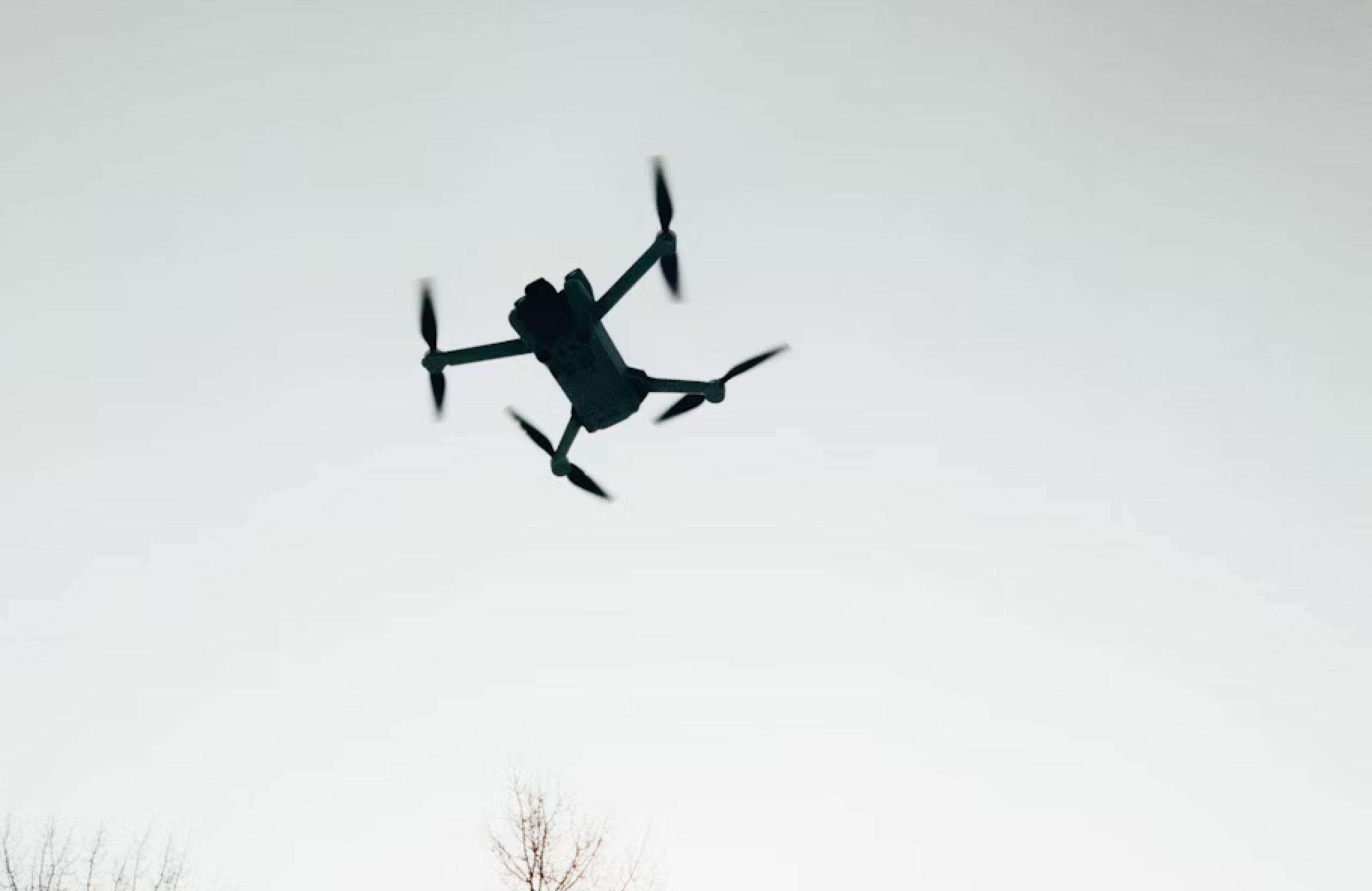 FX Productions Canada A quadcopter drone with RPAS certification is flying in the sky, its silhouette visible against a pale, clear background—perfect for aerial cinematography. Toronto Video Production Company
