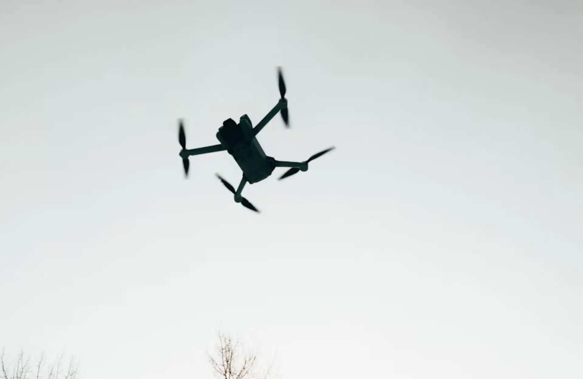 FX Productions Canada A quadcopter drone with RPAS certification is flying in the sky, its silhouette visible against a pale, clear background—perfect for aerial cinematography. Toronto Video Production Company