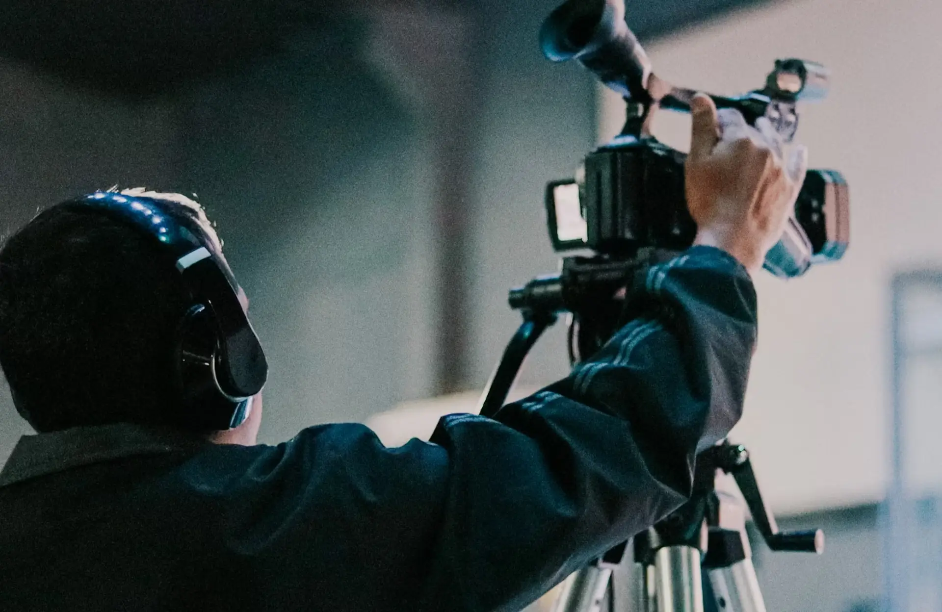 FX Productions Canada Person wearing headphones operates a video camera mounted on a tripod in an indoor setting with blurred background. Toronto Video Production Company