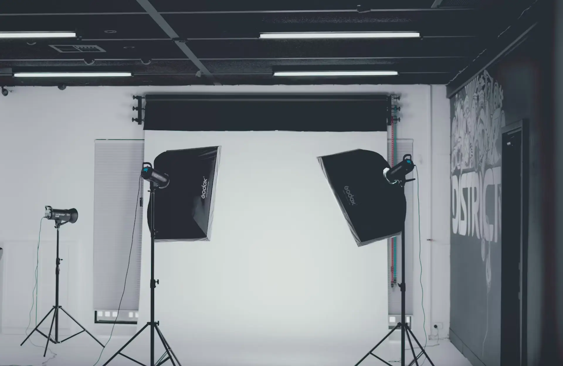 FX Productions Canada A photography studio setup with two large softbox lights and one smaller light on stands positioned in front of a white backdrop. Toronto Video Production Company