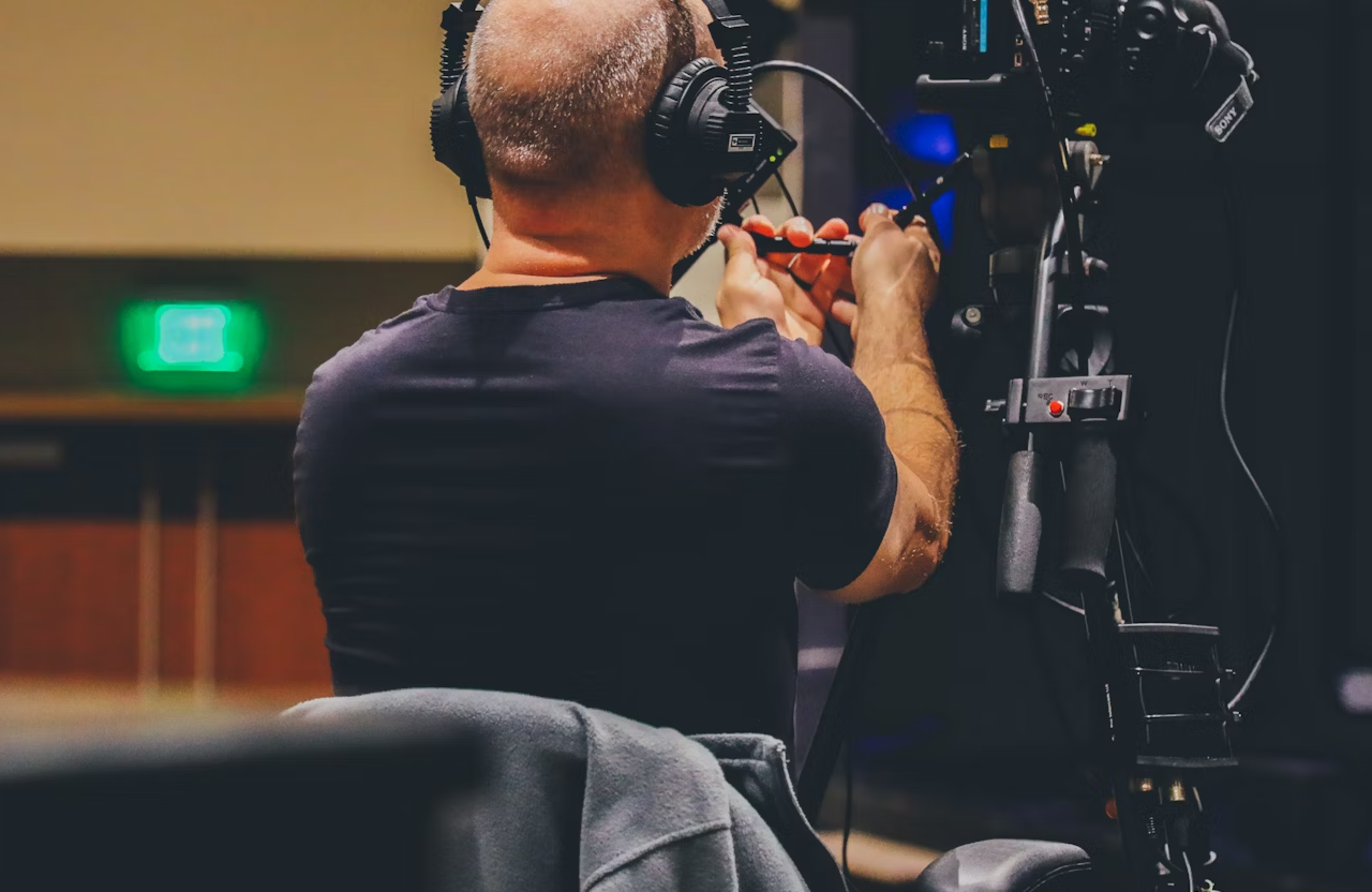 FX Productions Canada A person wearing headphones adjusts a professional video camera on a tripod in an indoor setting. Toronto Video Production Company