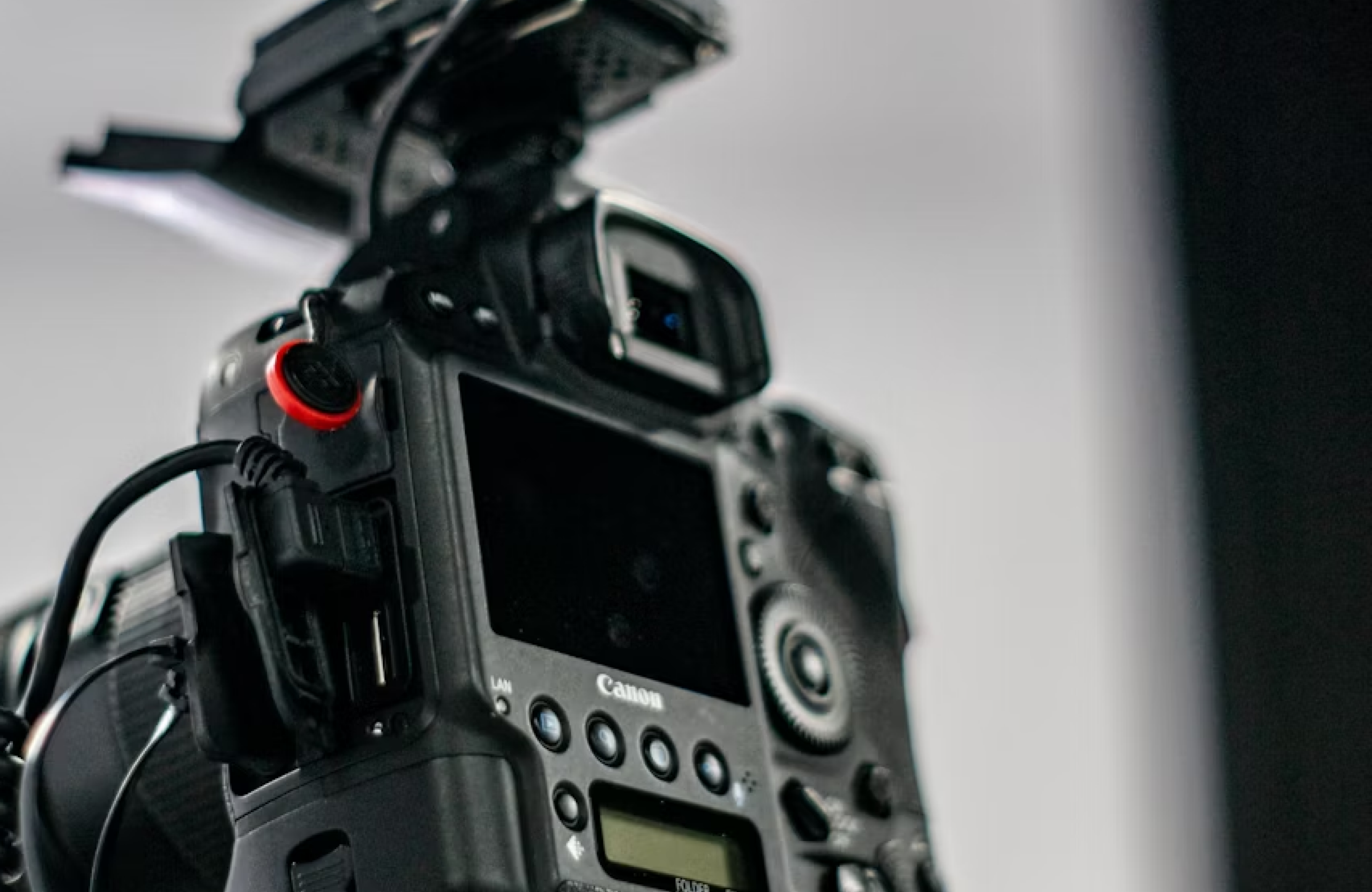 FX Productions Canada Close-up of the rear controls and display screen of a Canon DSLR camera with various buttons, dials, and an external device attached on top. Toronto Video Production Company